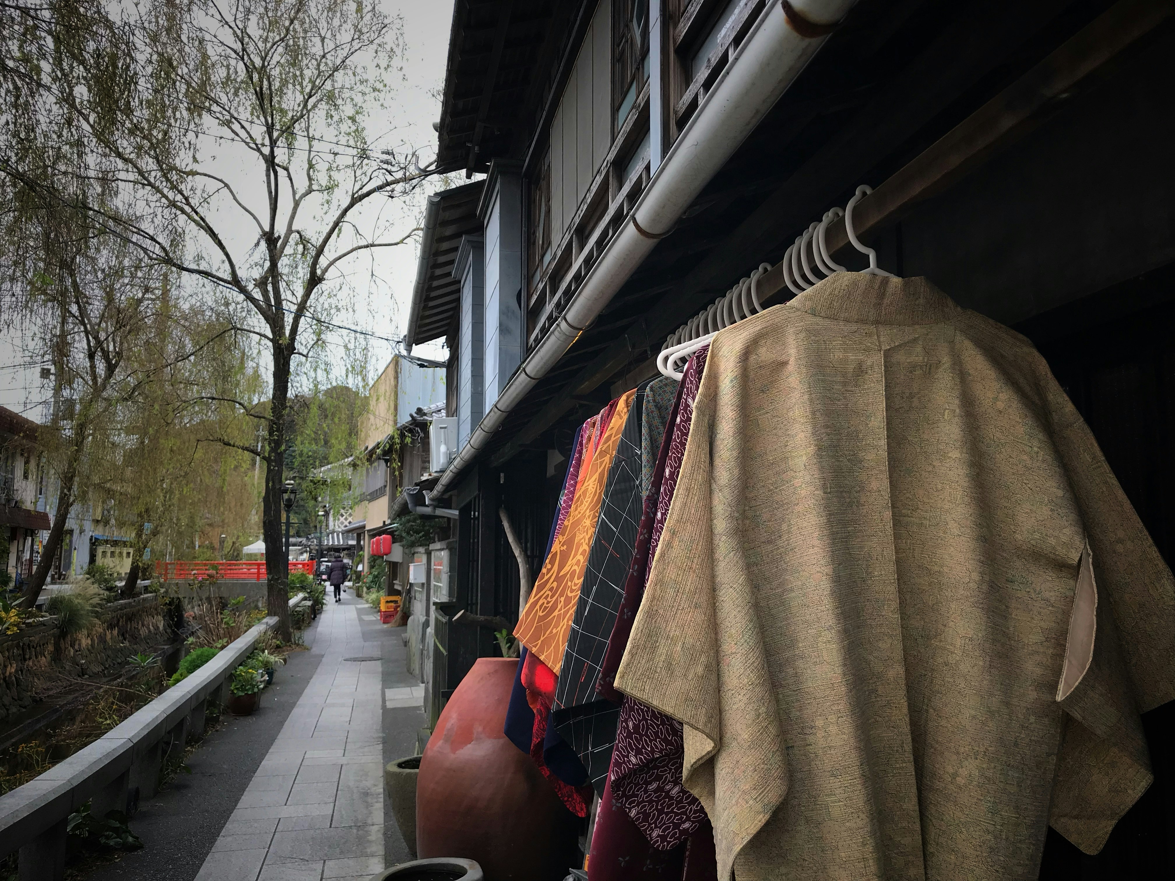 路地の軒先に掛かるコートと傘
