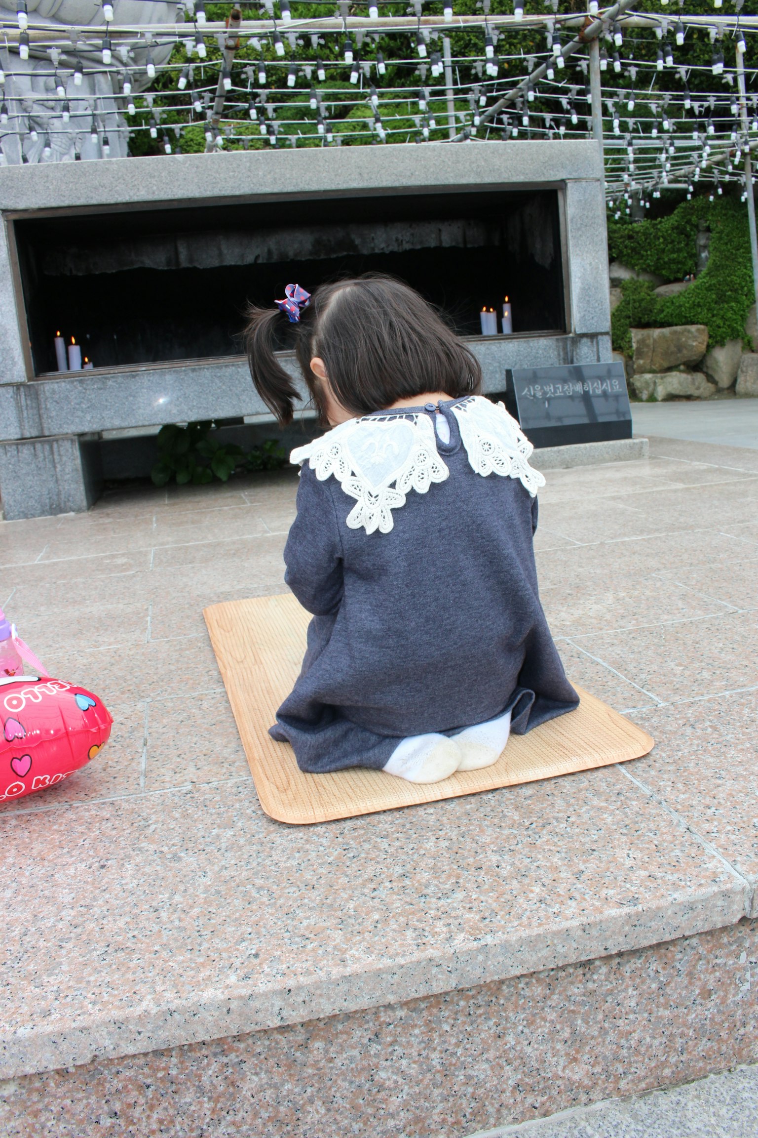 孩子坐在墊子上，穿著有蕾絲領子的裝飾性毛衣