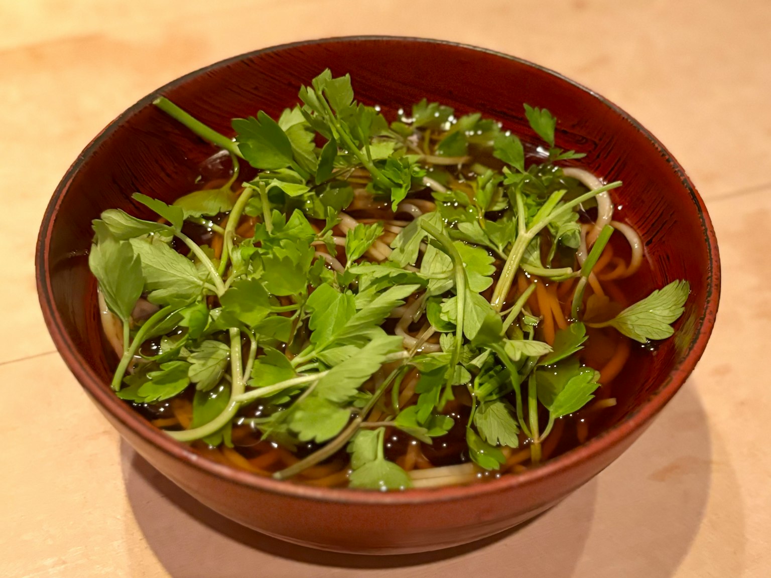Noodles sottili guarniti con erbe fresche in una ciotola marrone