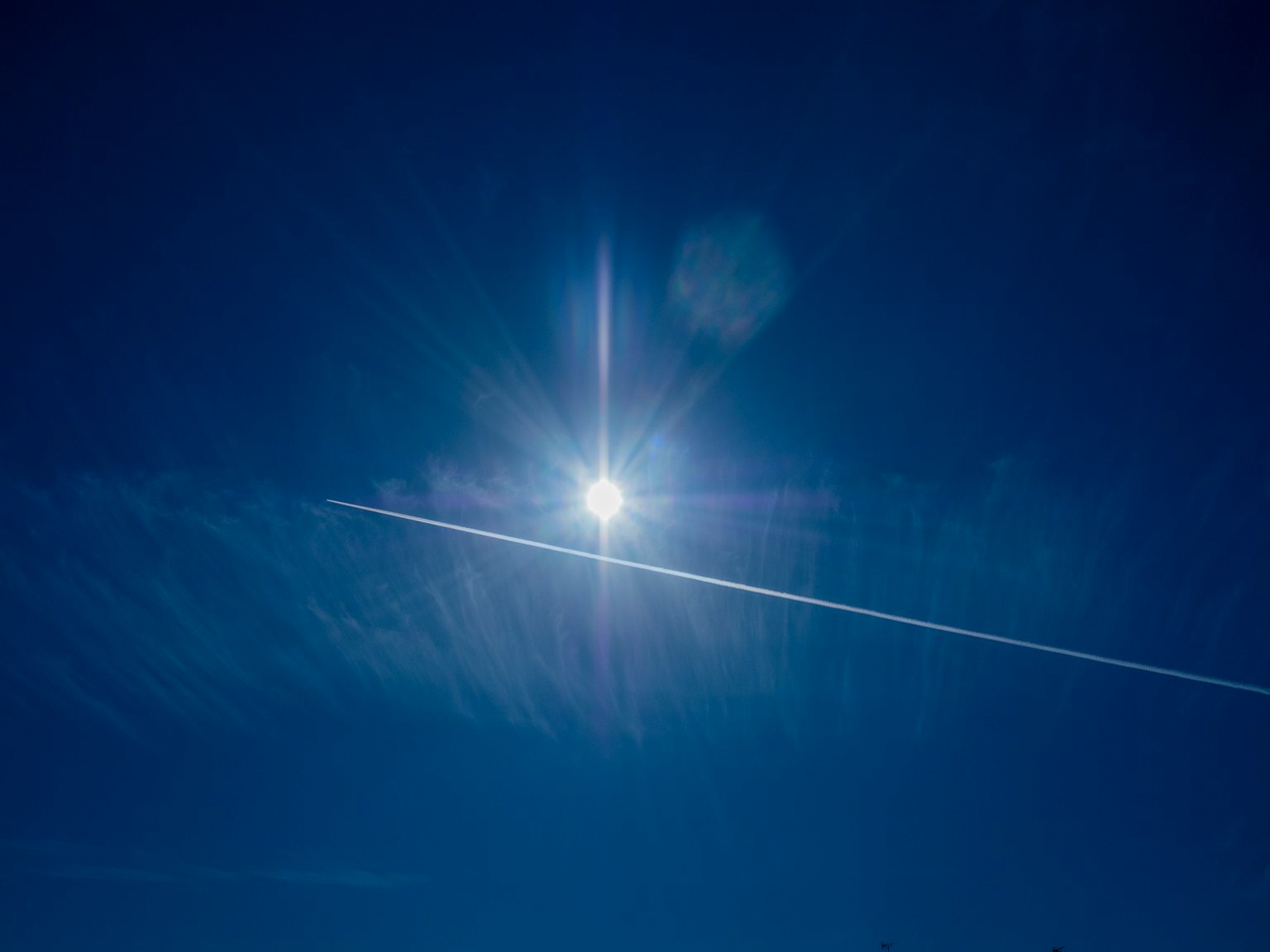 Helle Sonne scheint in einem klaren blauen Himmel mit Kondensstreifen