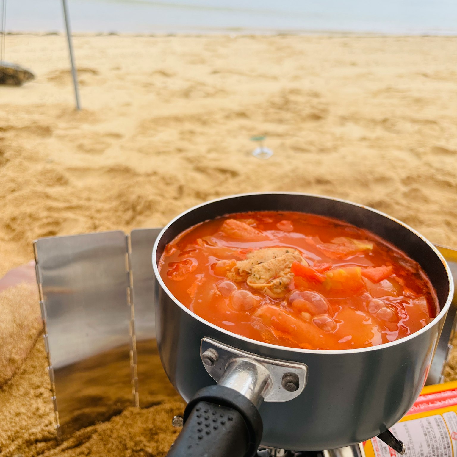 A pot of tomato soup cooking on the beach