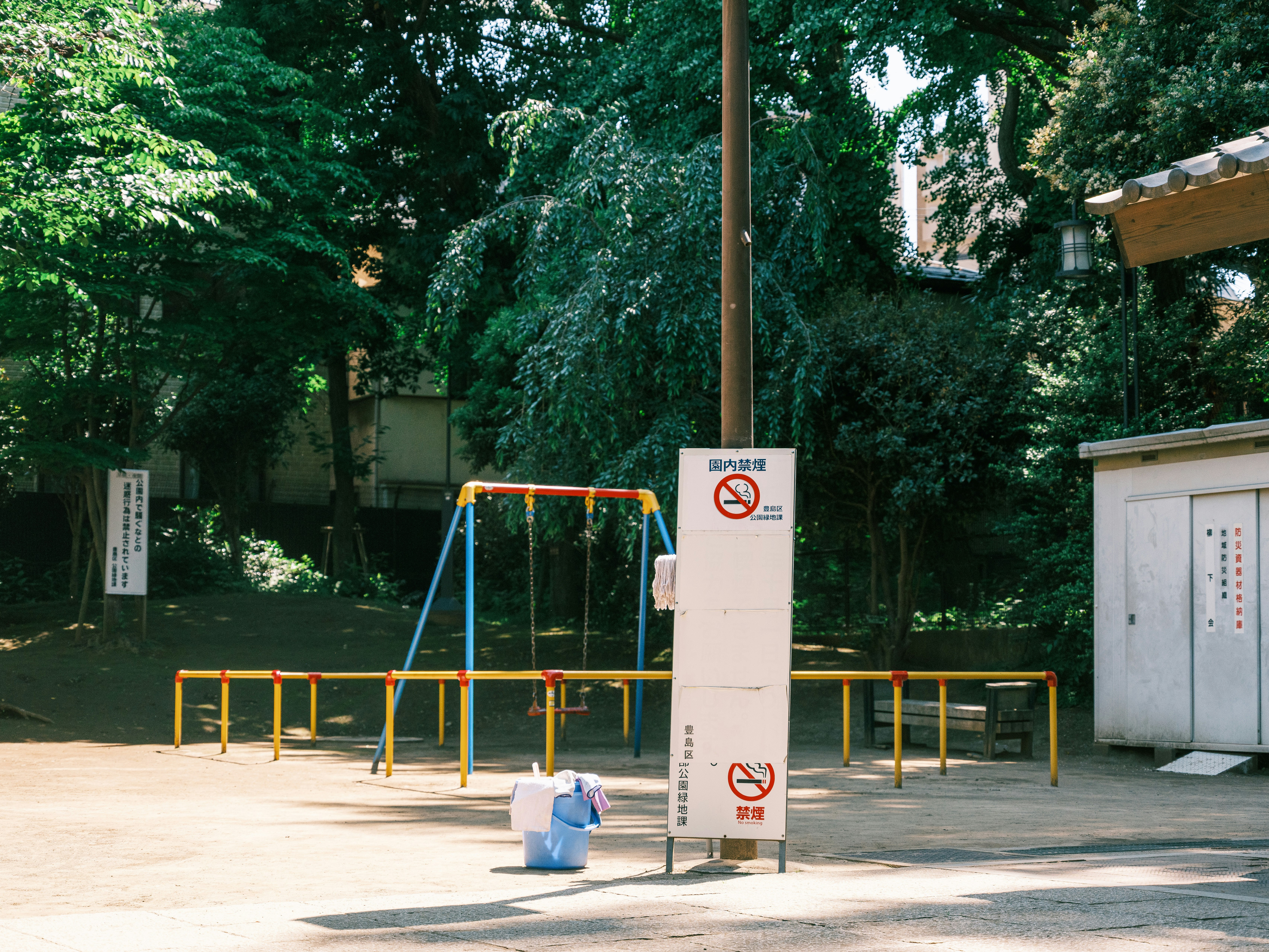 Area giochi all’aperto con attrezzature e cartelli di avviso in un parco verde