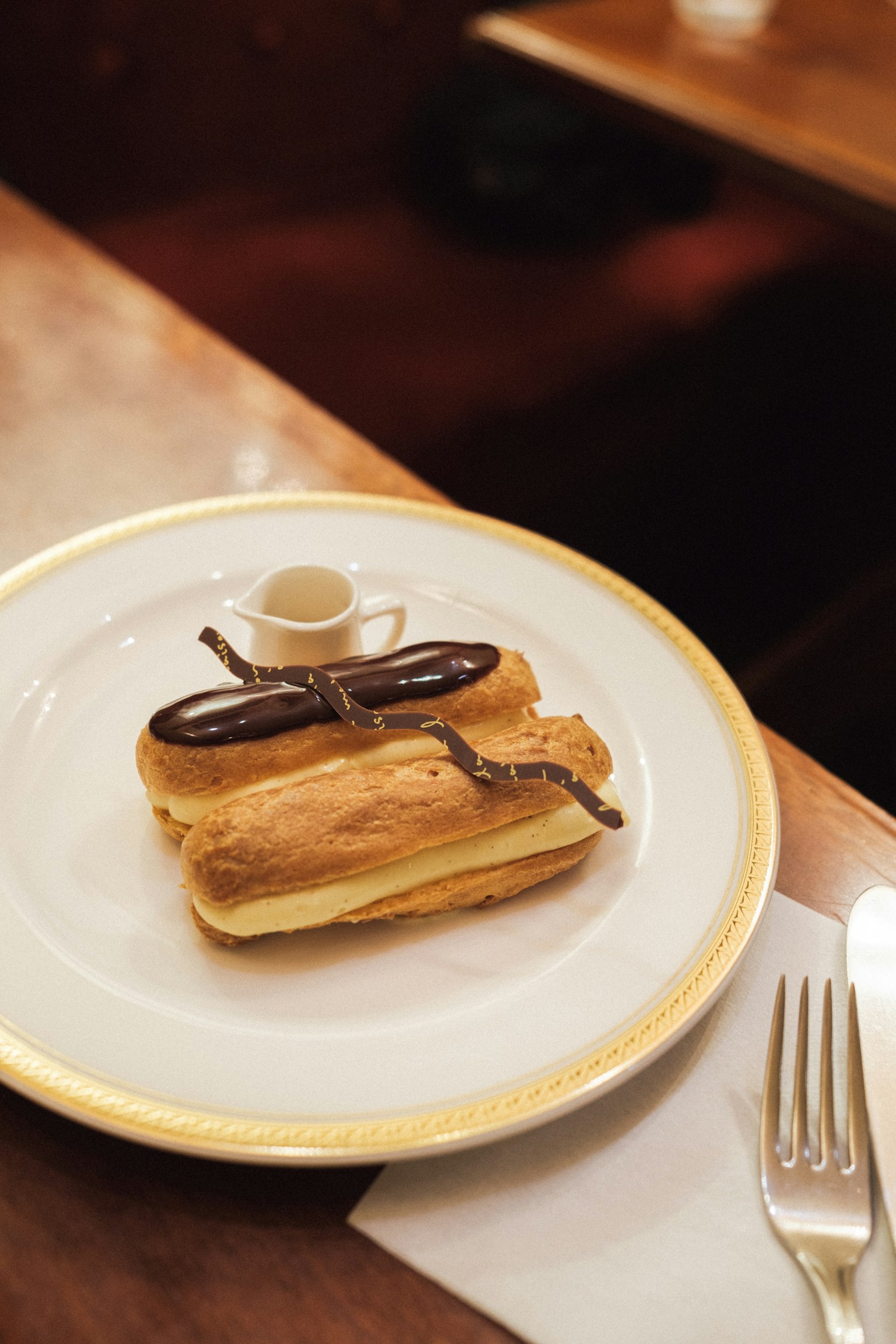 Eclair di atas piring dengan cangkir kopi kecil