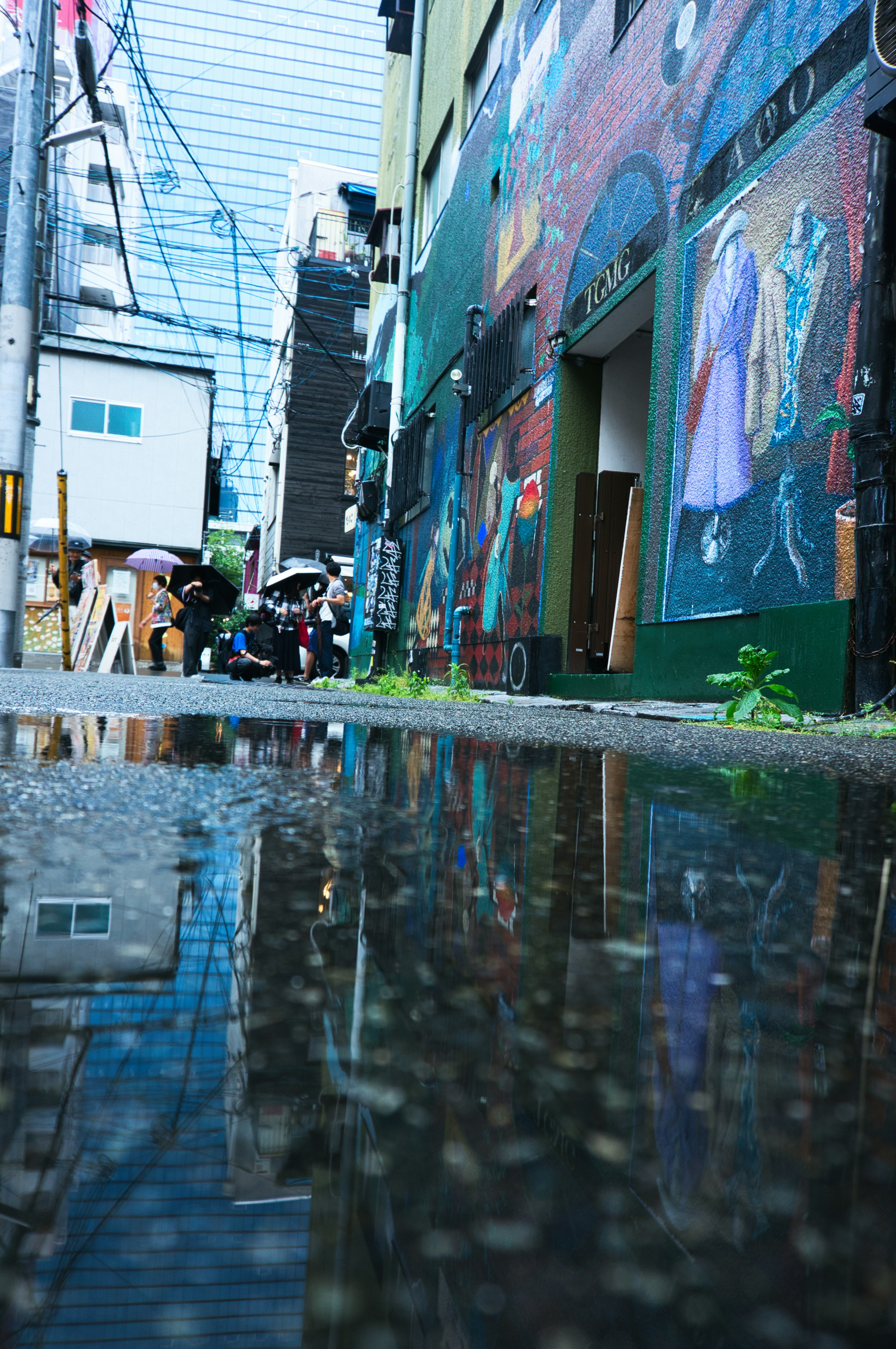 雨上がりの中崎町の路地に広がる壁のアートと水たまり