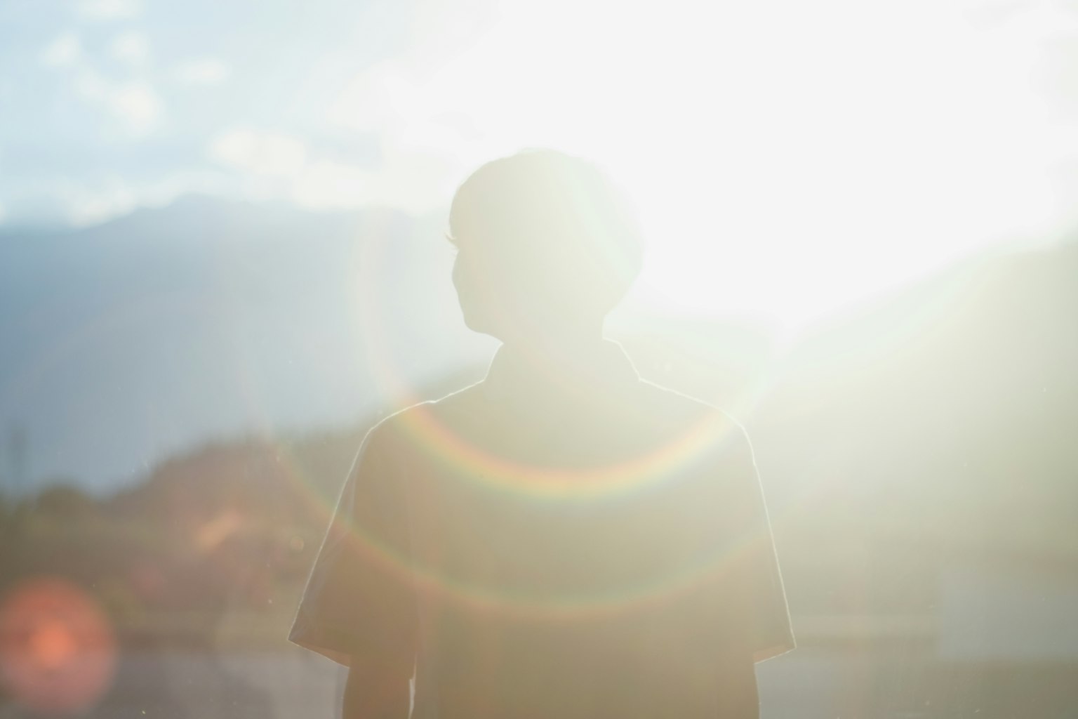 Silhouette di una persona in piedi contro un sole luminoso