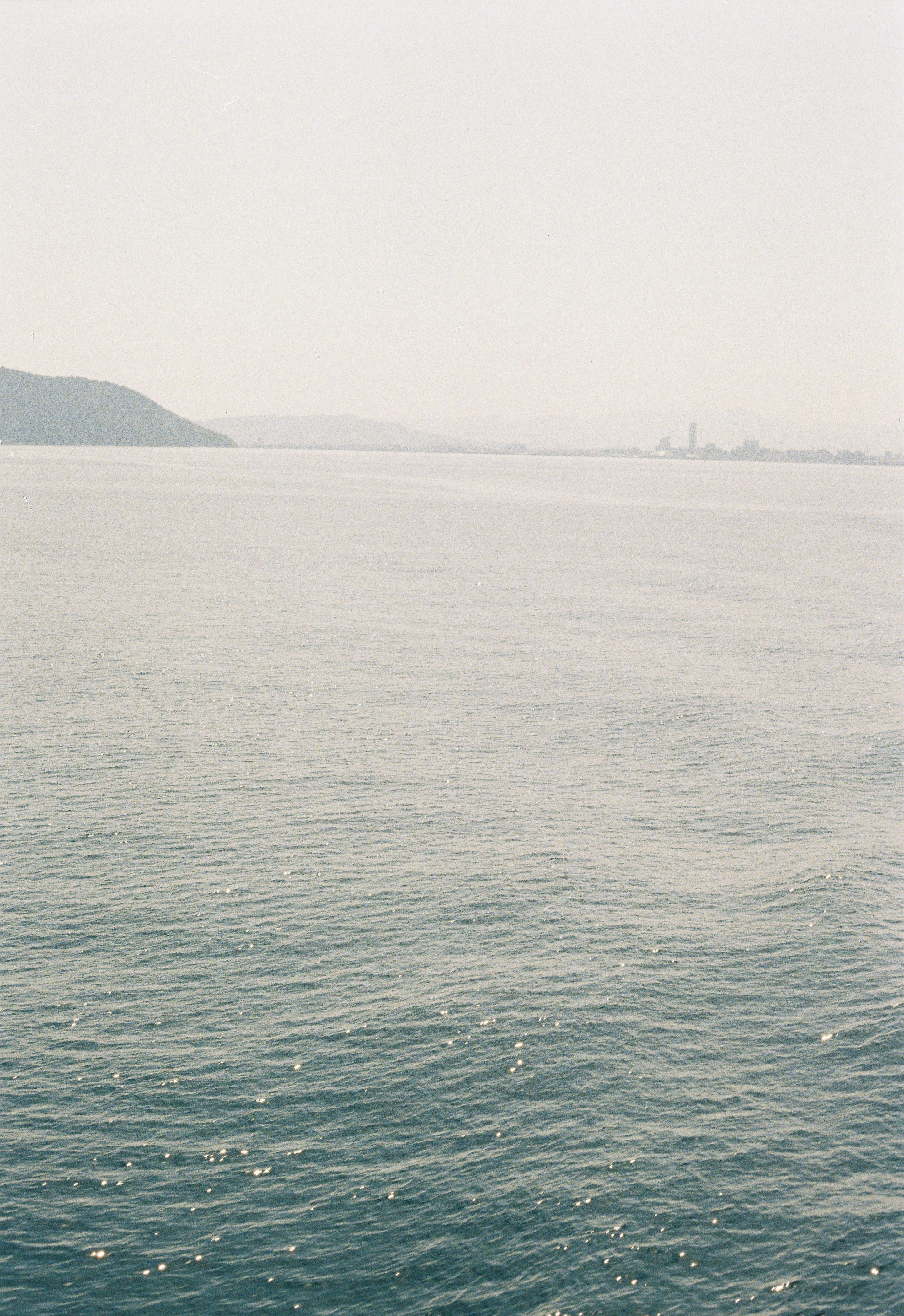 海面と遠くに見える岬・港の風景