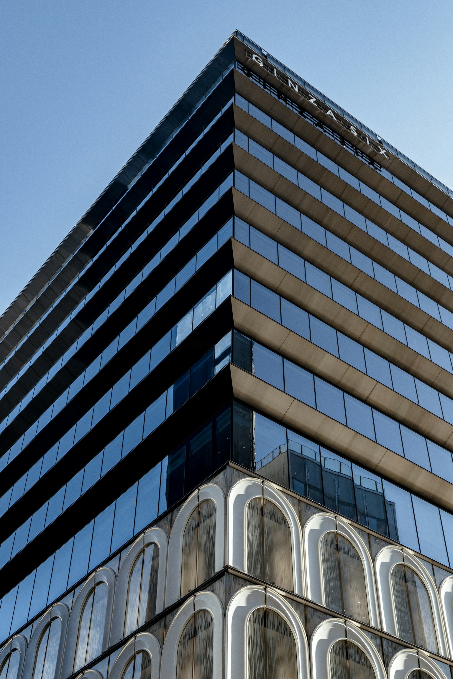 Exterior moderno de un edificio visto desde un ángulo diagonal bajo un cielo azul con diseño de vidrio y concreto