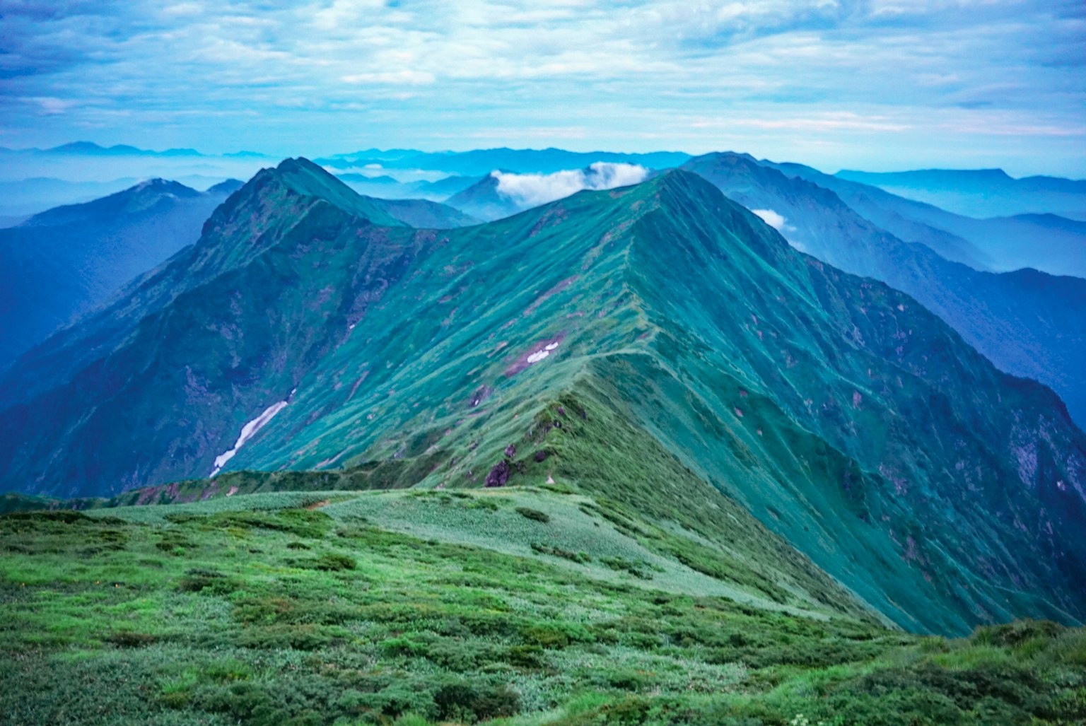 Malersicher Blick auf üppige grüne Berggipfel unter einem blauen Himmel mit Wolken