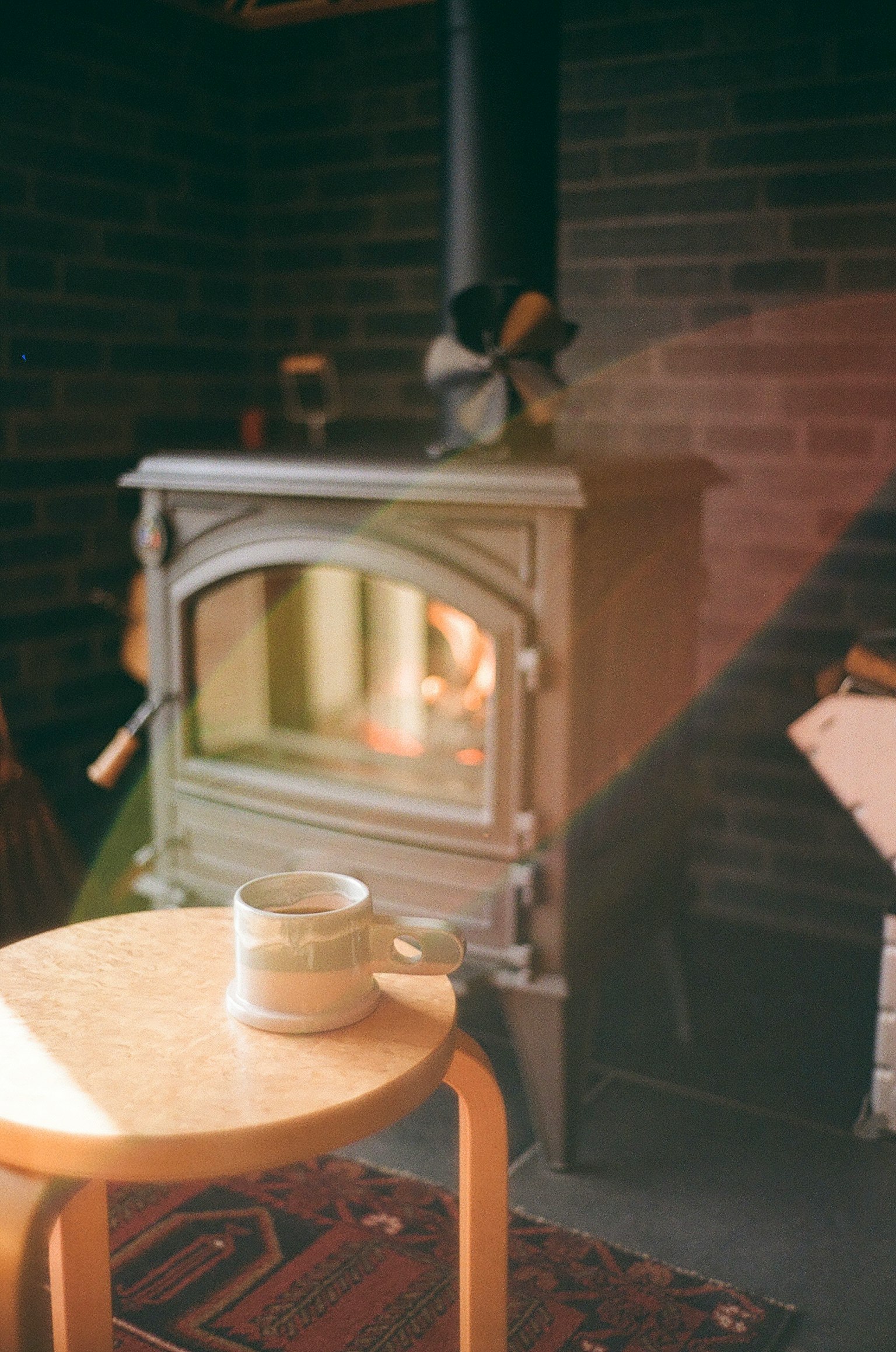 Table en bois avec une tasse devant un poêle lumière chaude dans un espace confortable
