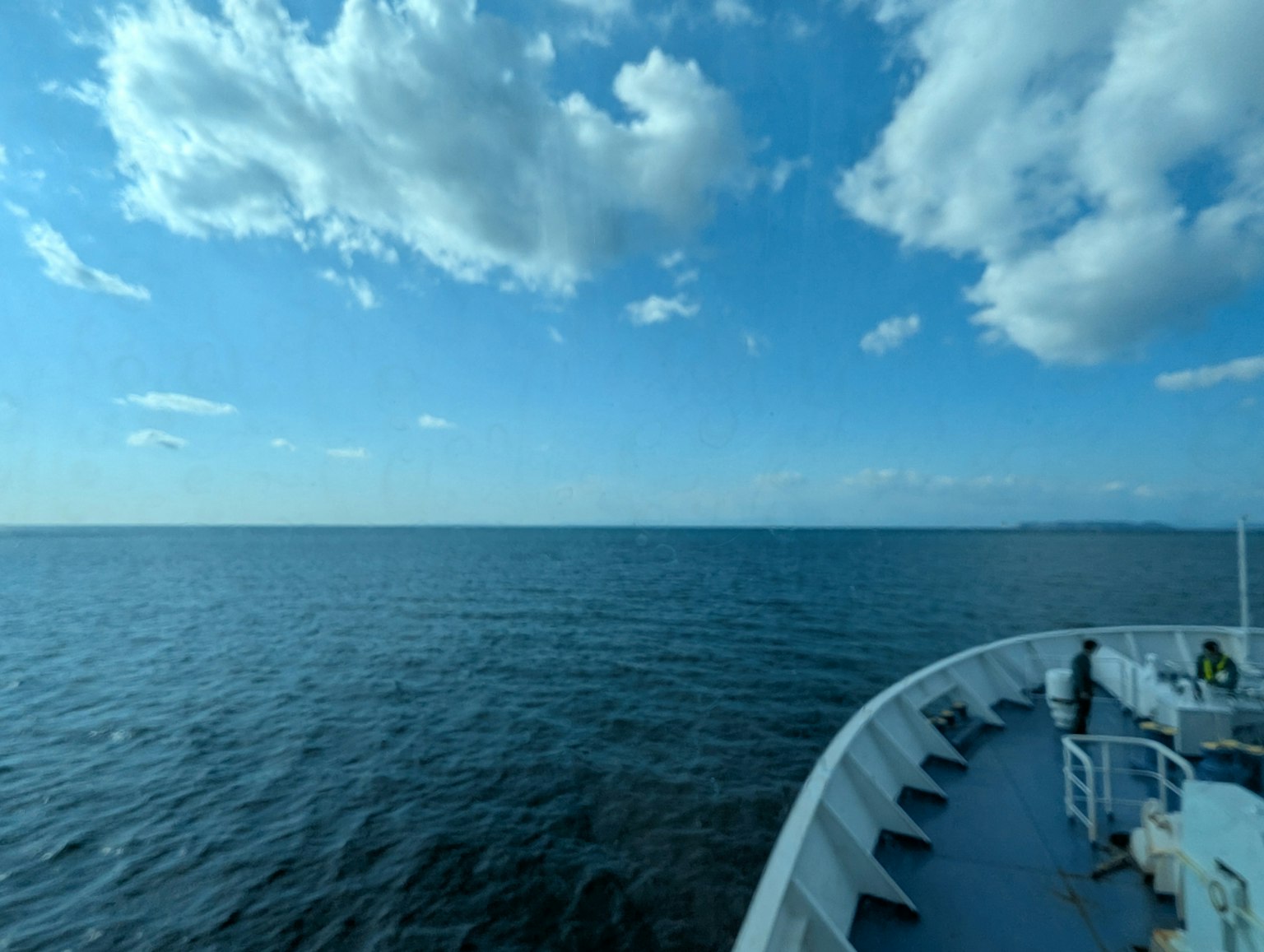 Una vista del mare blu e del cielo luminoso con il lato di una nave visibile