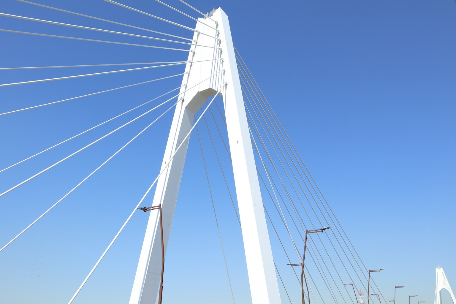 Menara jembatan kabel putih di bawah langit biru cerah