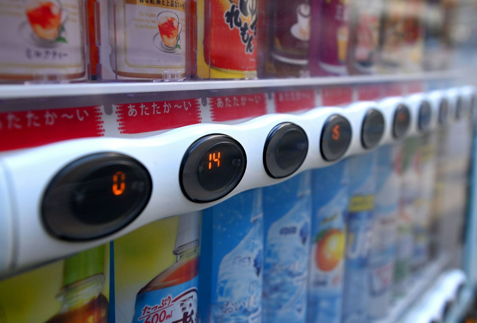 Primo piano dei pulsanti di un distributore automatico e delle lattine di bevande