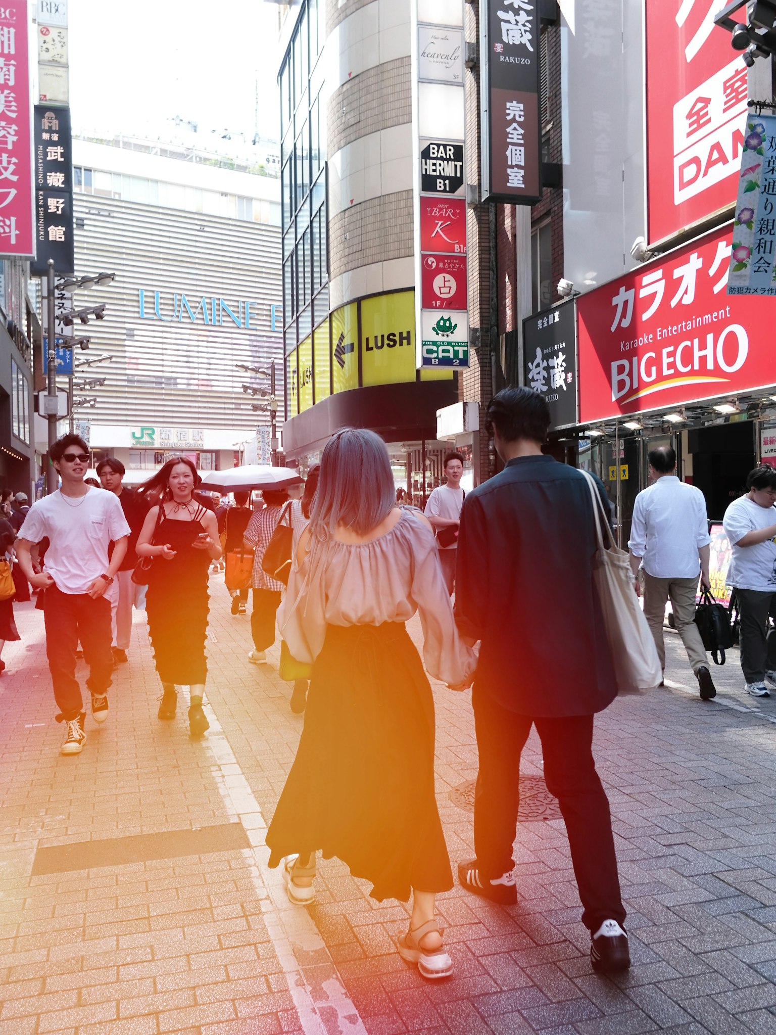 Couple walking in a bustling street with bright signs and diverse outfits