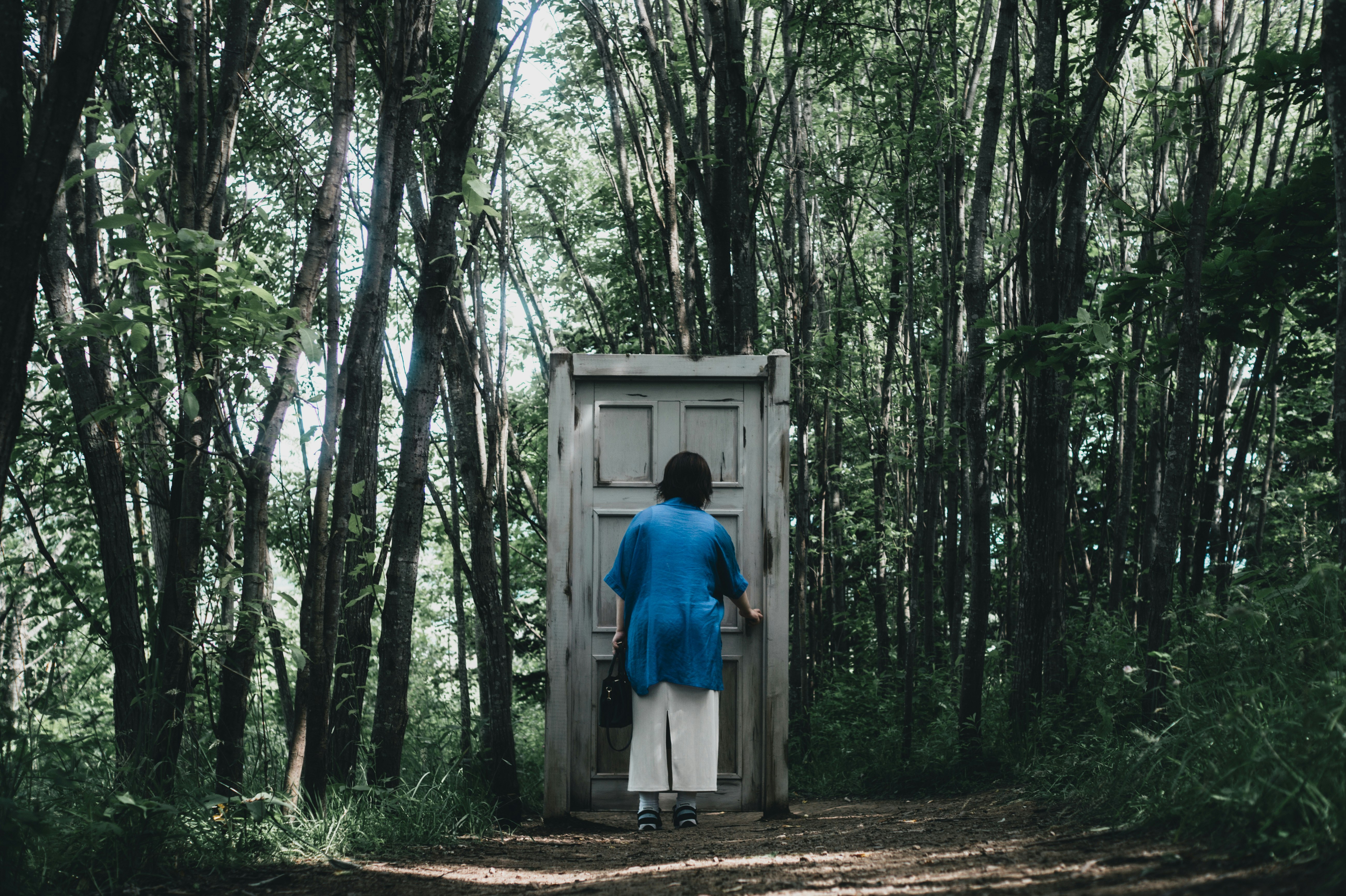 森の小道を歩く人物と小さな扉のある箱