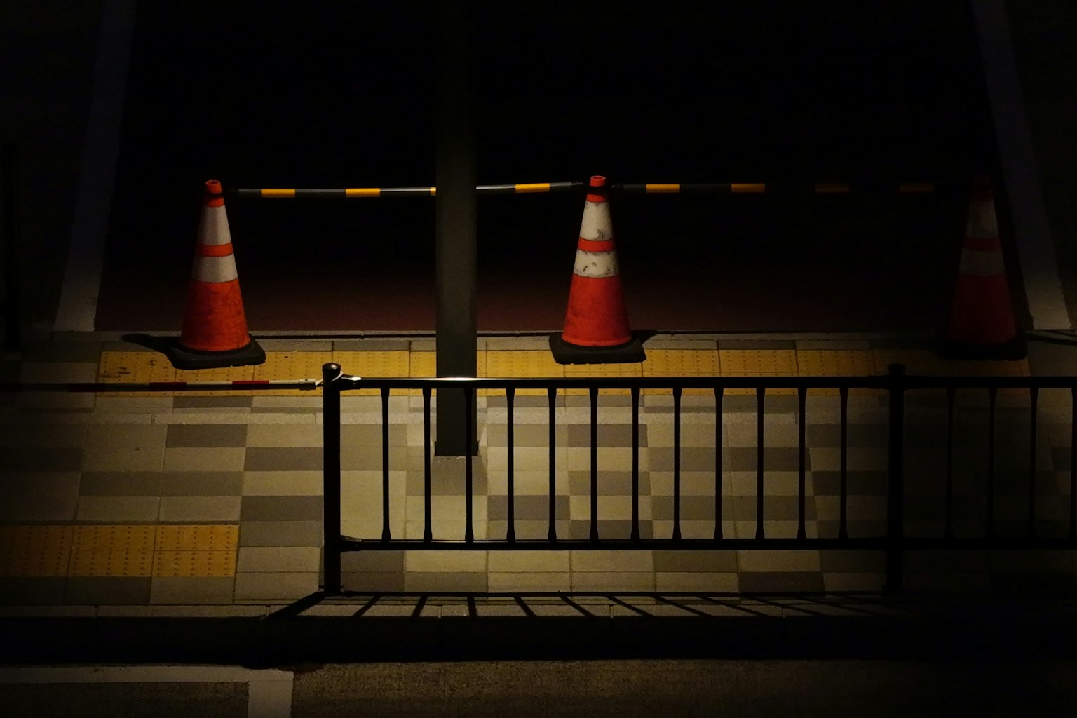 暗い場所にあるオレンジ色のコーンと金属製のフェンス