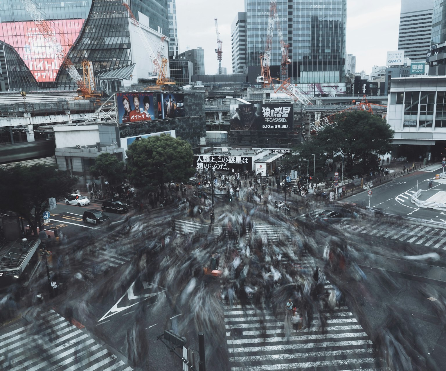 Menschenmenge überquert die Shibuya-Kreuzung mit Wolkenkratzern im Hintergrund