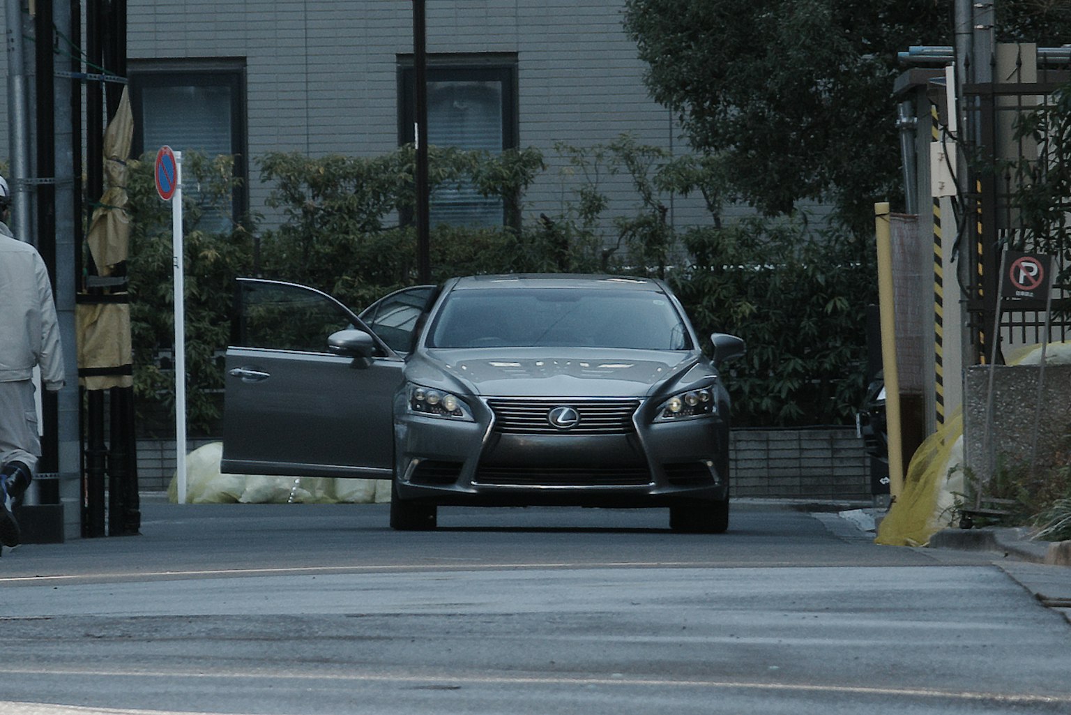 Gray luxury car with an open door driving down the street