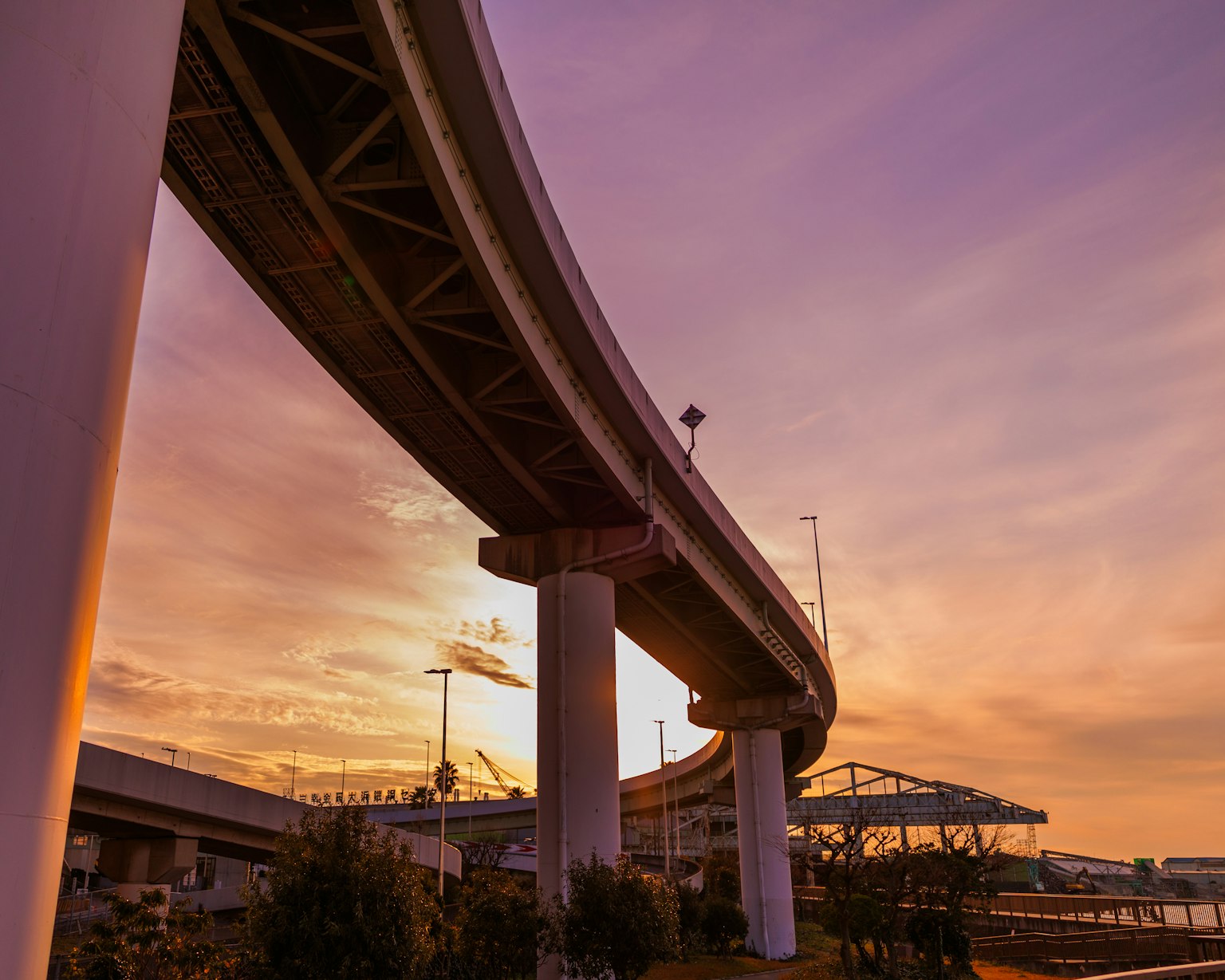 Autopista elevada curva bajo un cielo de atardecer con pilares de soporte