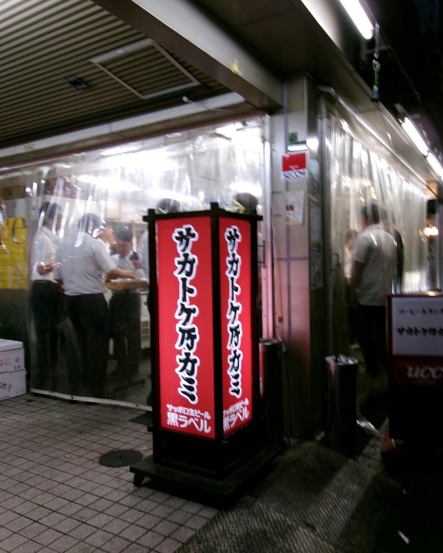 日本の飲食店の外観 明るい赤い看板と透明なビニールカーテン 店内で食事をする人々