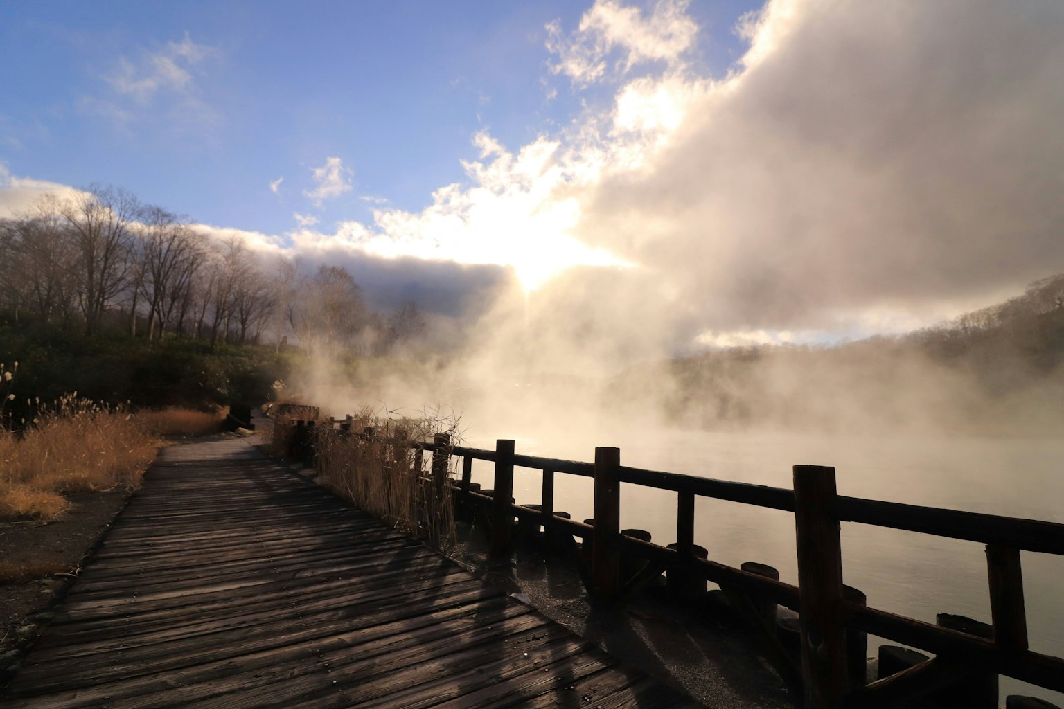 Vista panoramica di un lago nebbioso con un sentiero in legno