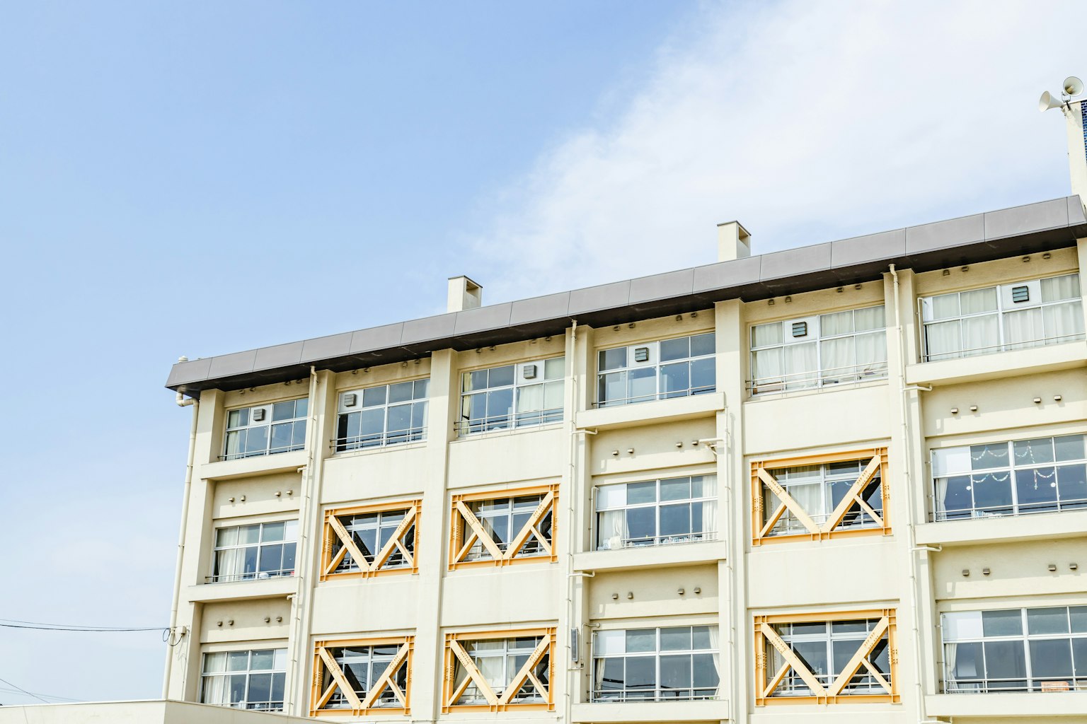 Vue extérieure d'un bâtiment moderne sous un ciel bleu avec des designs de fenêtres en bois uniques