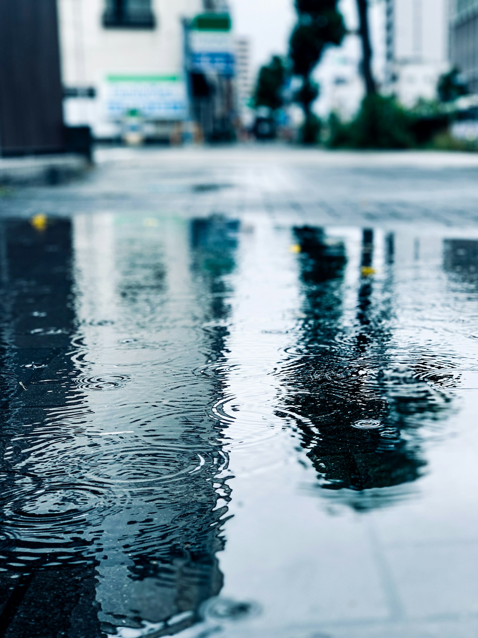 Reflet dans une flaque d'eau sur une rue de la ville sous la pluie avec des gouttes de pluie