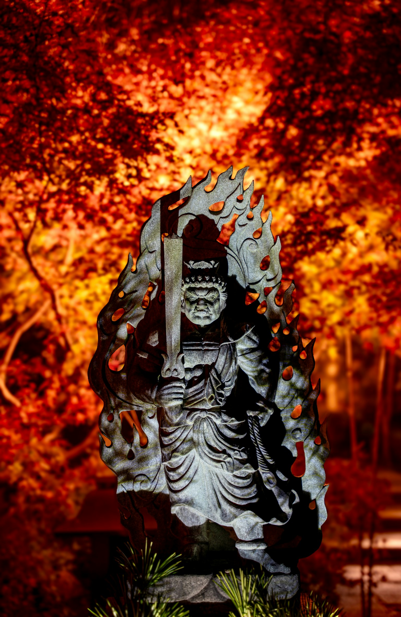 Escultura de una deidad con follaje otoñal vibrante de fondo