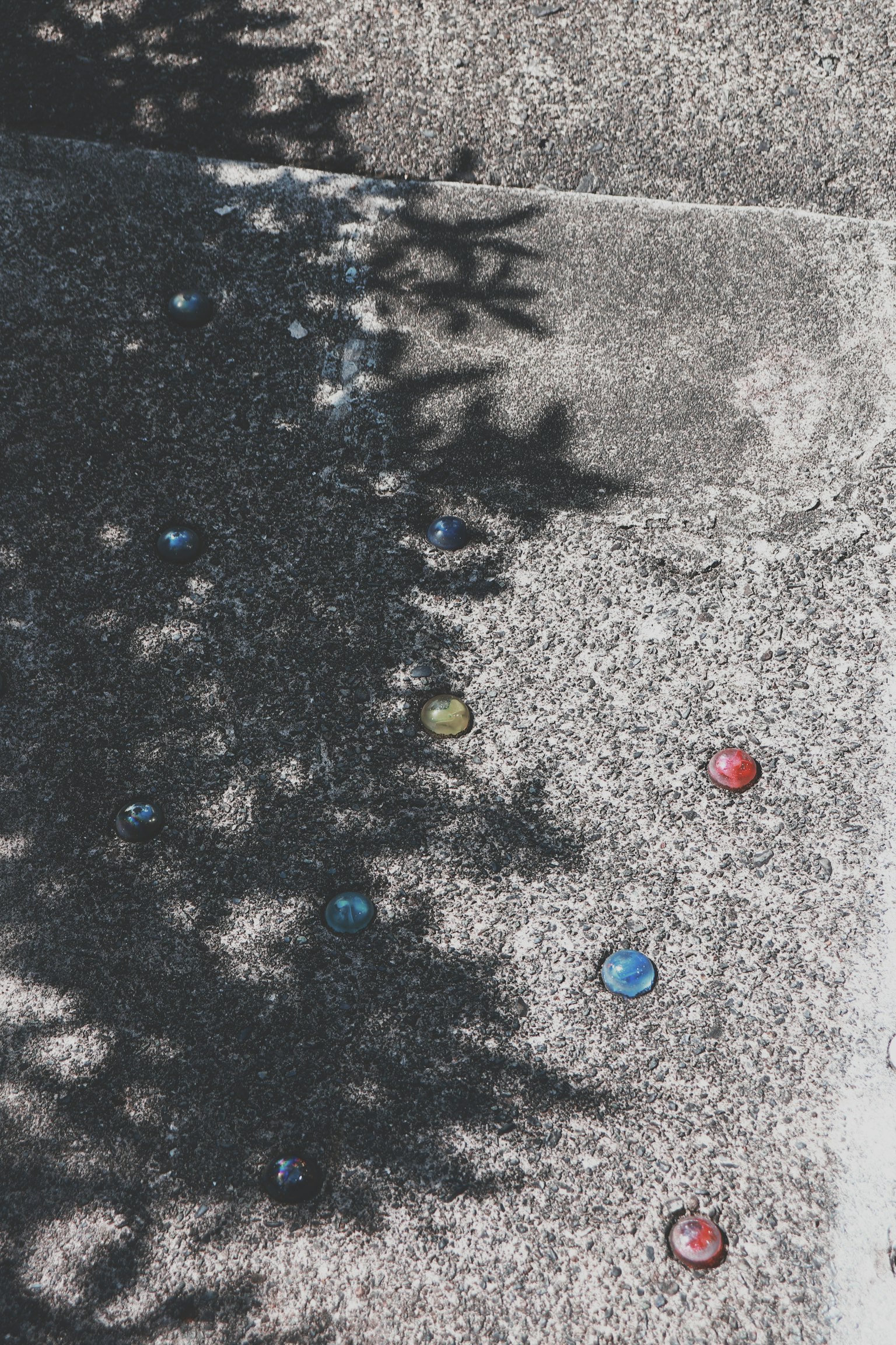 Marble colorate sparse su un pavimento in cemento con ombre