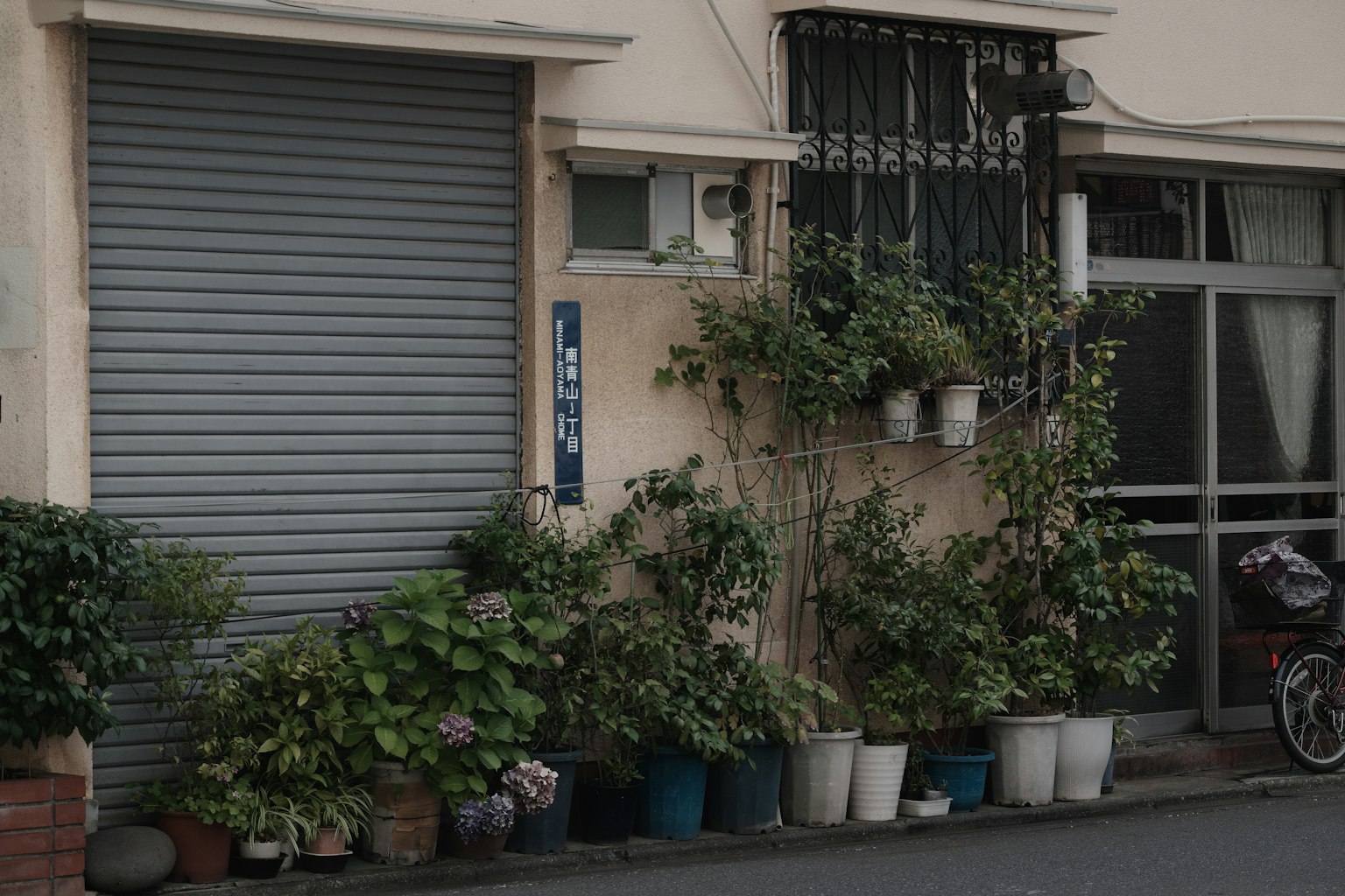 Persiana grigia con piante in vaso davanti a un edificio residenziale