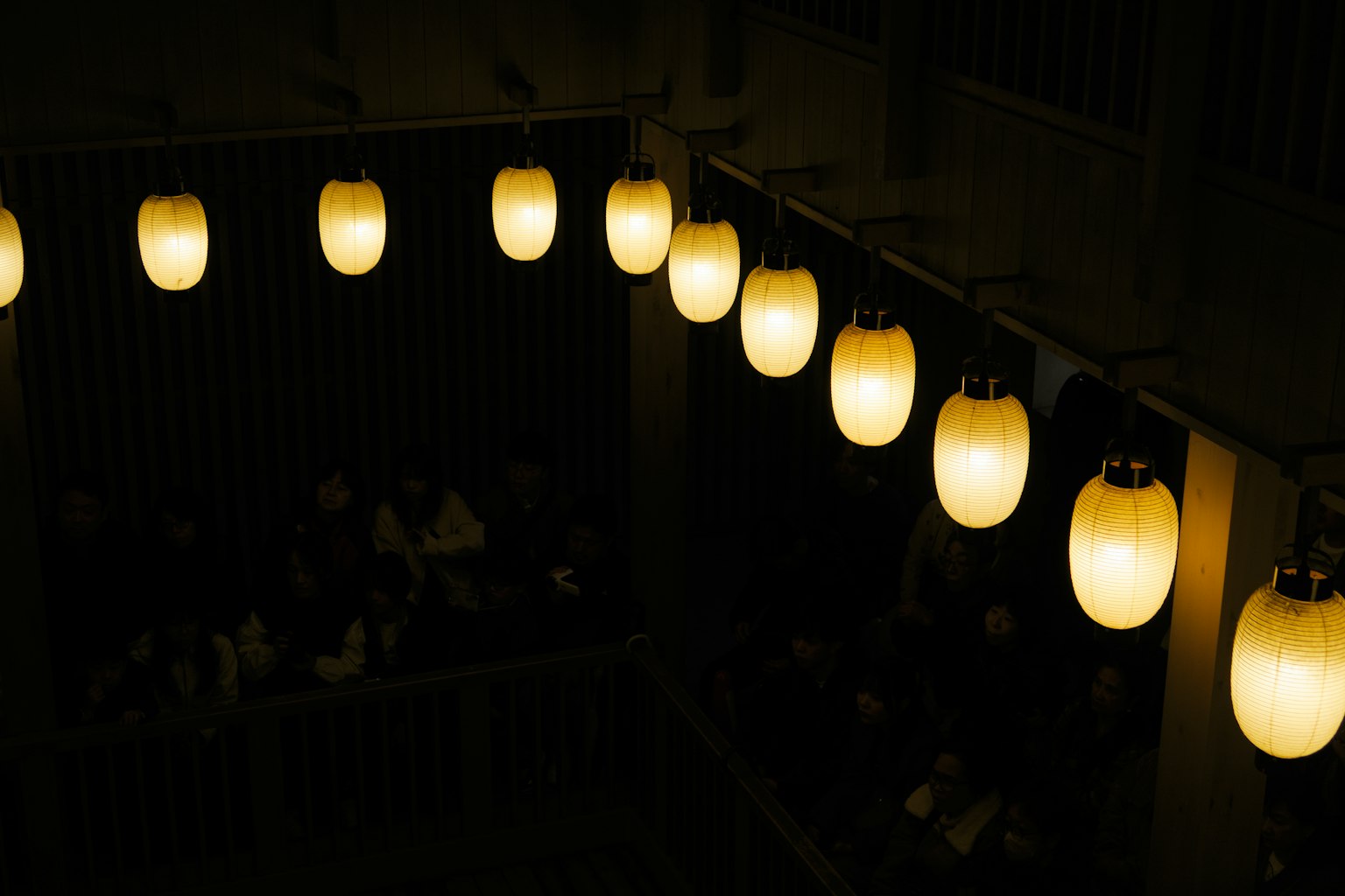 暗い背景に浮かぶ温かい色合いの提灯が並ぶ光景