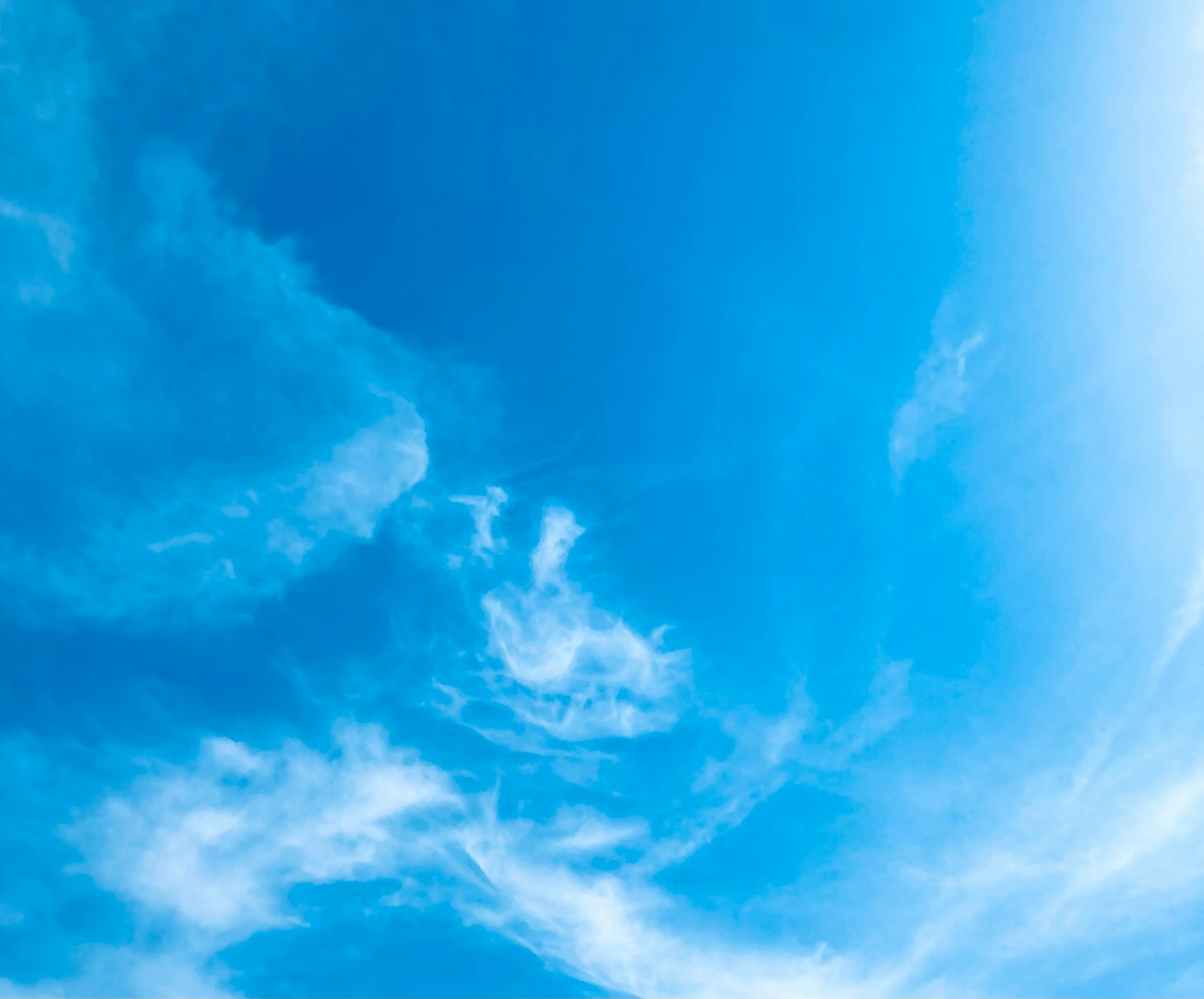 Vast blue sky with wispy white clouds