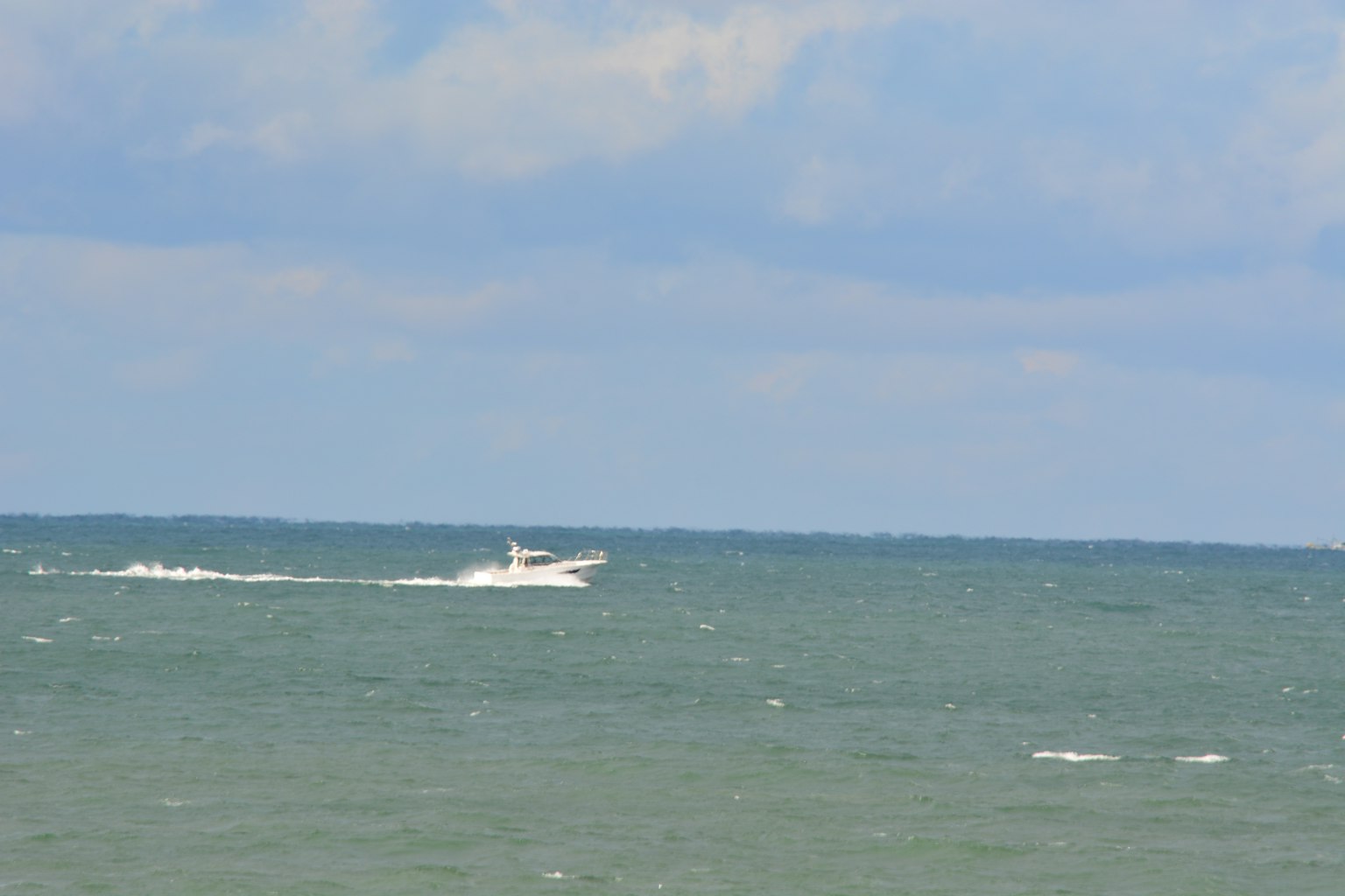 Un bote blanco navegando en el mar bajo un cielo azul