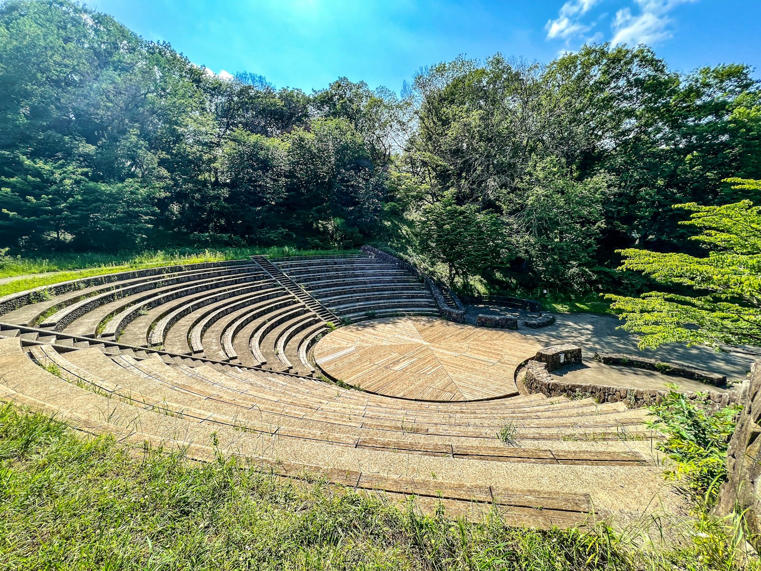 Circular amphitheater surrounded by lush greenery and blue sky