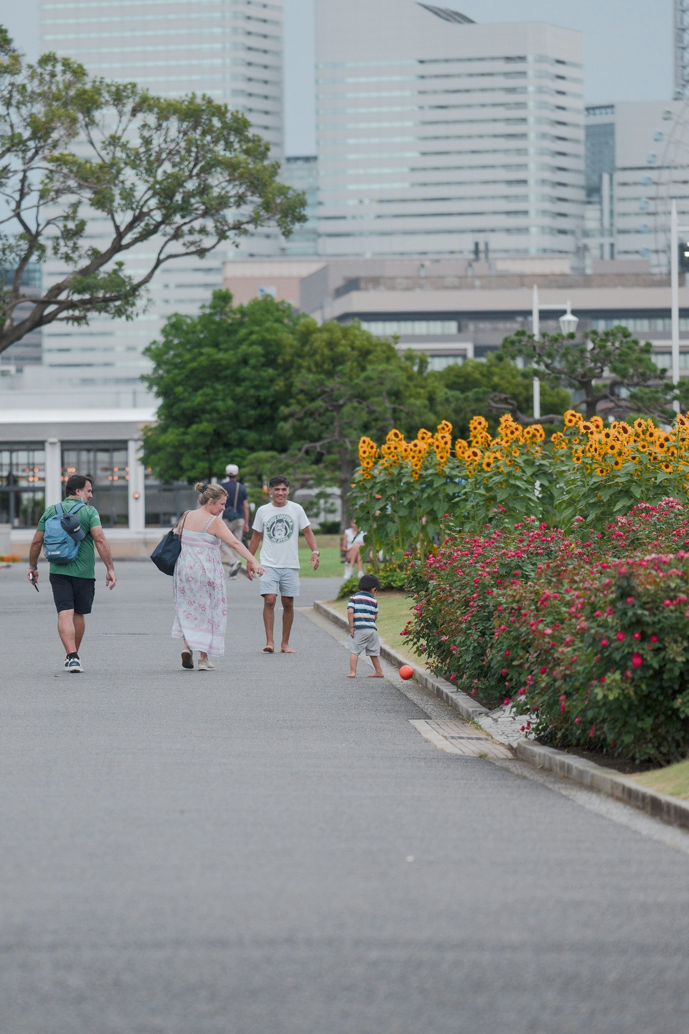 Famiglia che cammina in un parco con fiori e grattacieli sullo sfondo