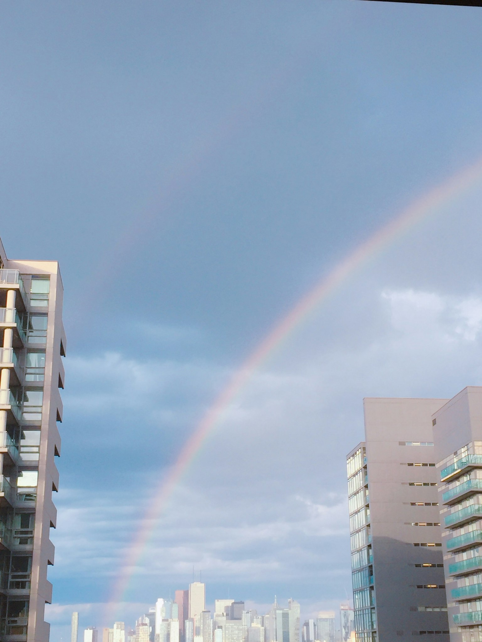 Un arcobaleno che si estende tra i palazzi sotto un cielo nuvoloso