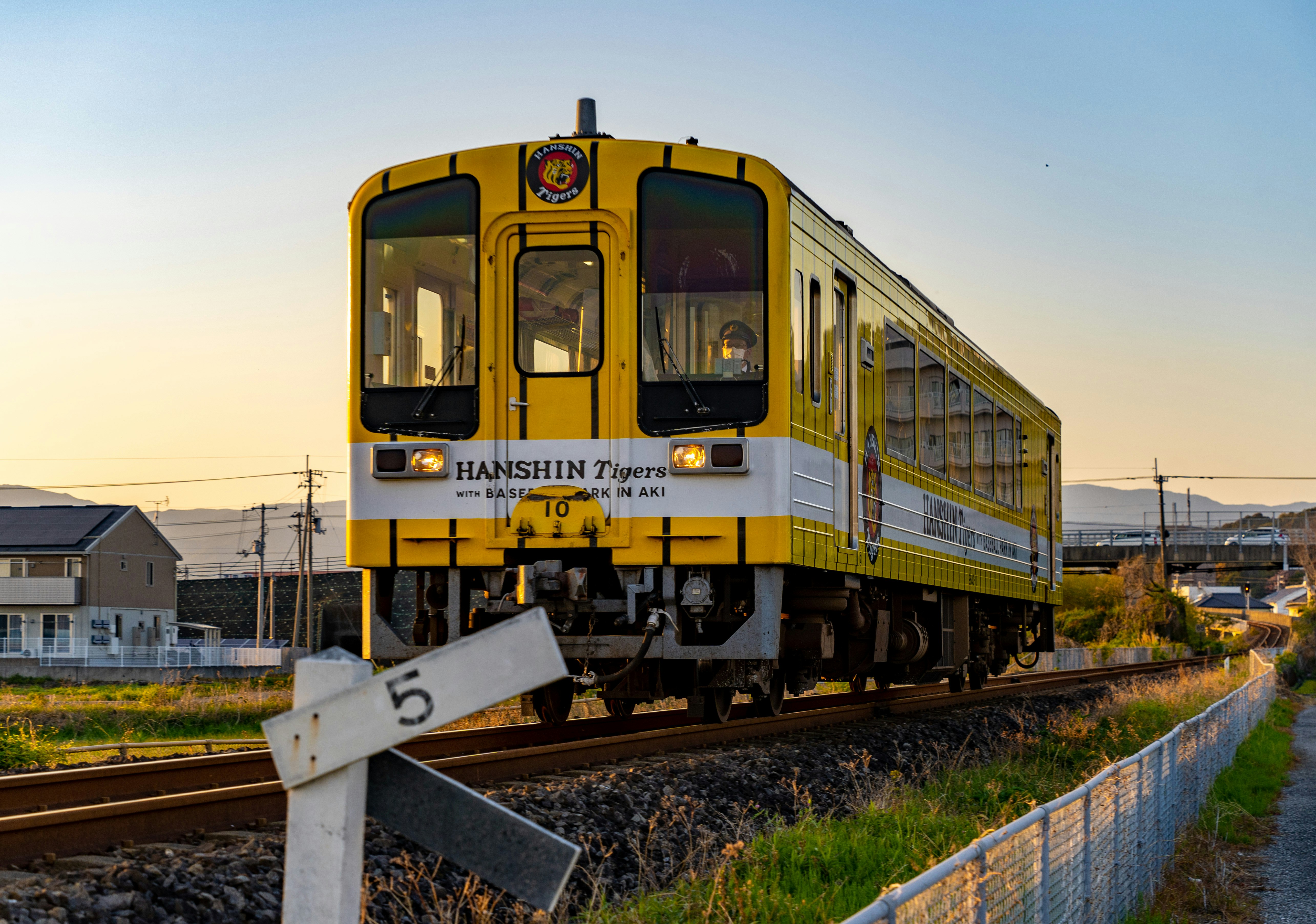 夕暮れの線路を走る黄色い列車