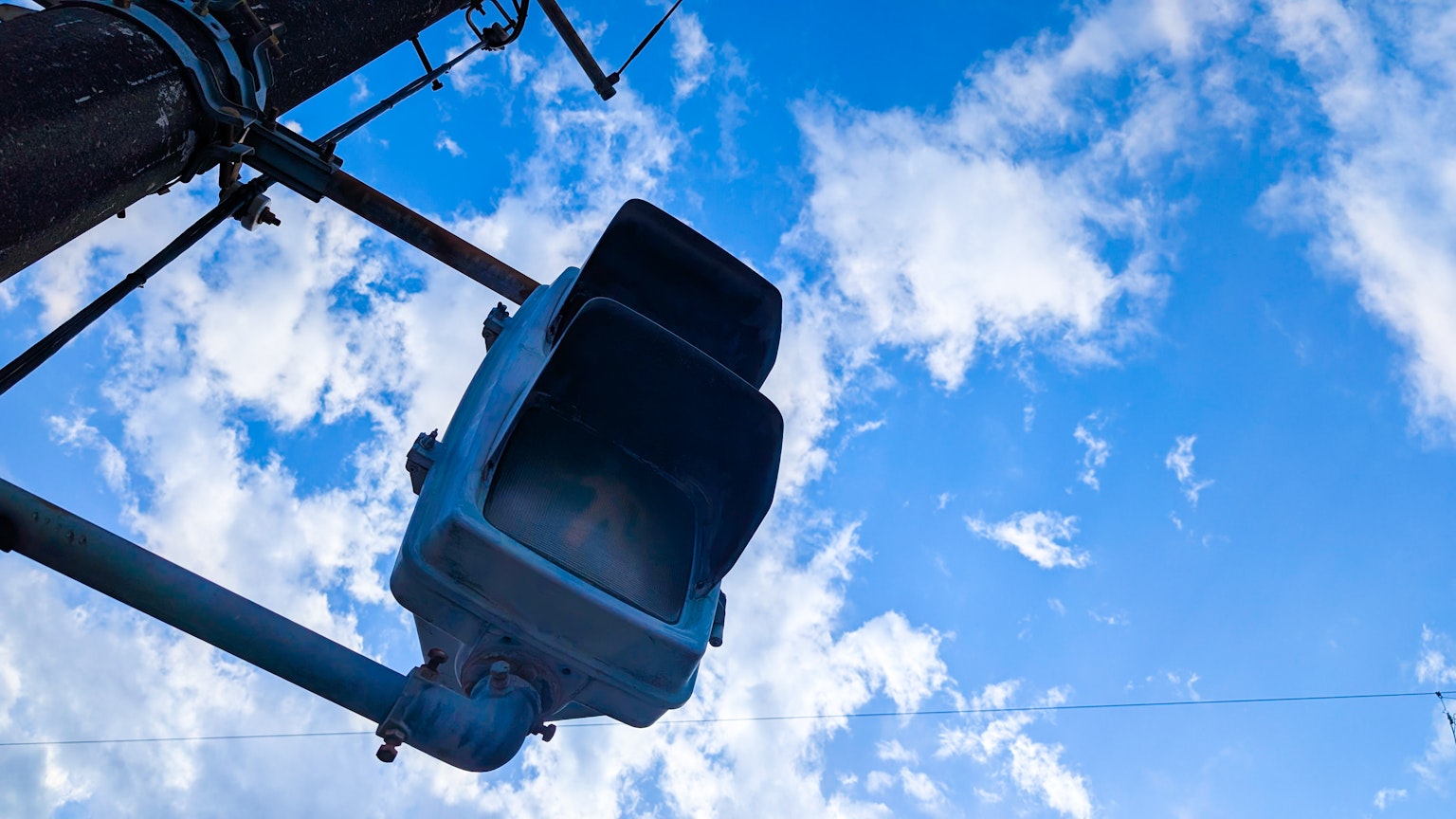 Image of a traffic signal against a blue sky with clouds