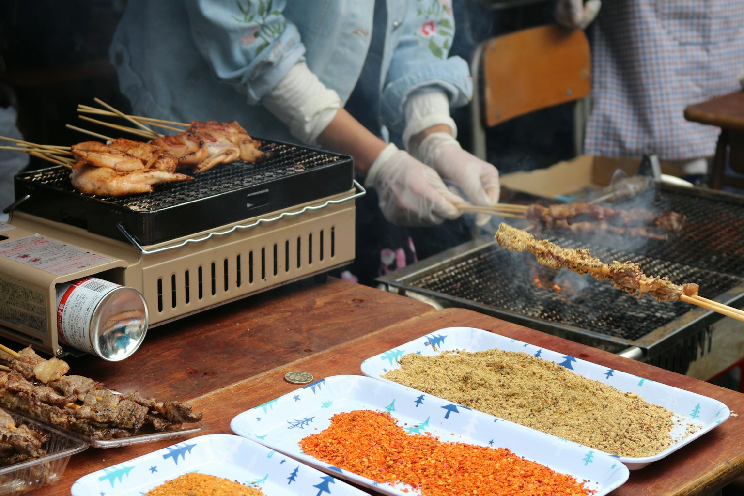 Scena di un venditore di strada che griglia carne su spiedini con spezie esposte