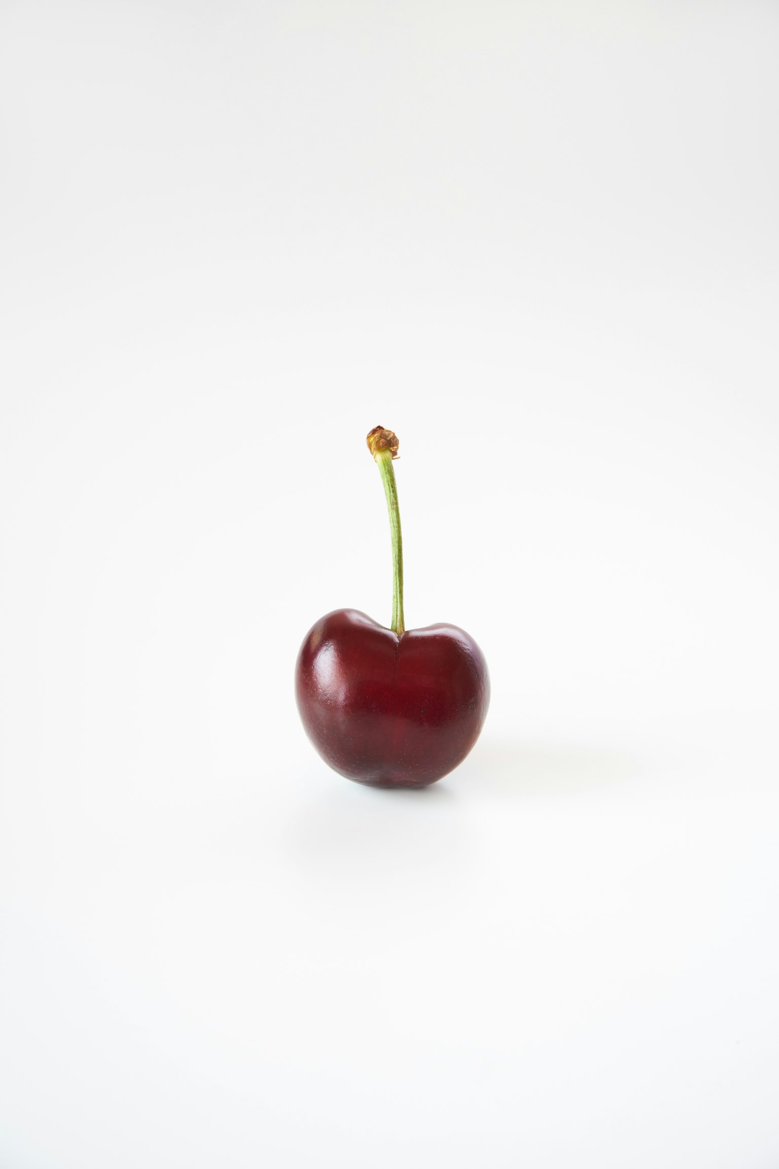 Một quả cherry đỏ đứng trên nền trắng
