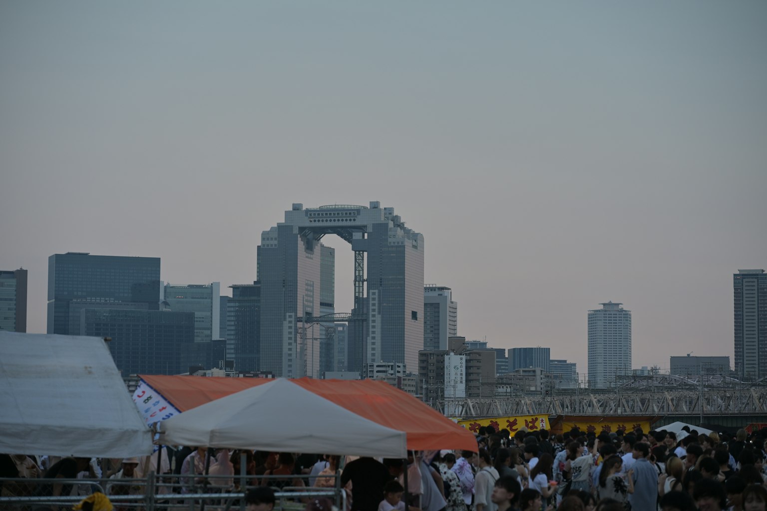 黃昏的城市天際線，展示了獨角獸高達雕像和帳篷