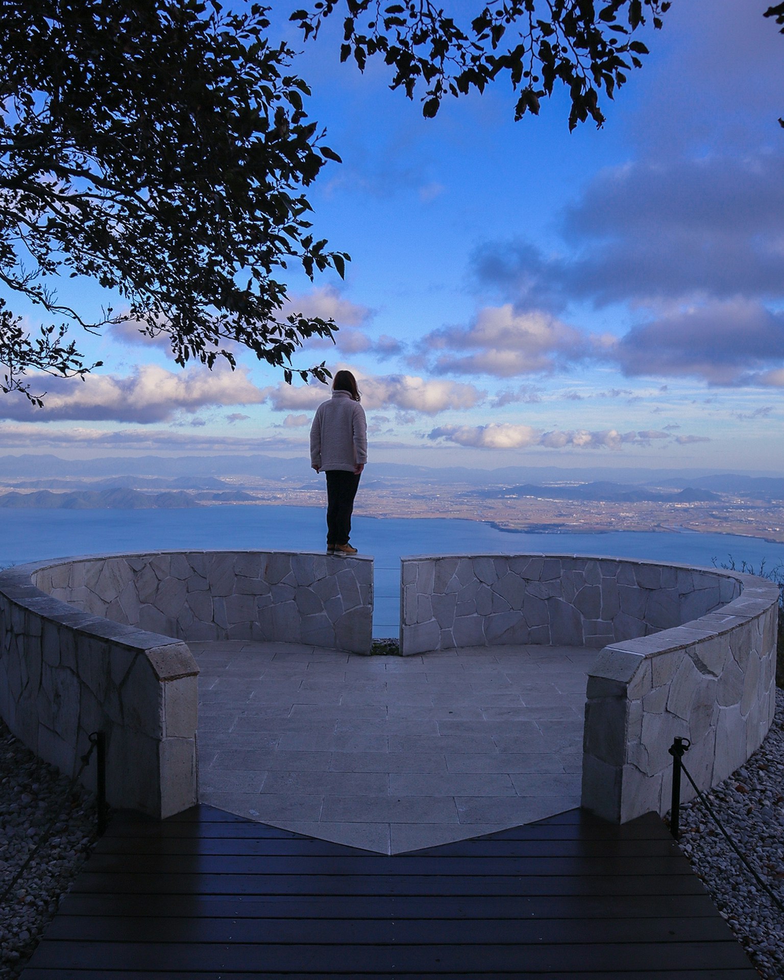 Una donna in piedi su un punto panoramico a forma di cuore con uno sfondo panoramico