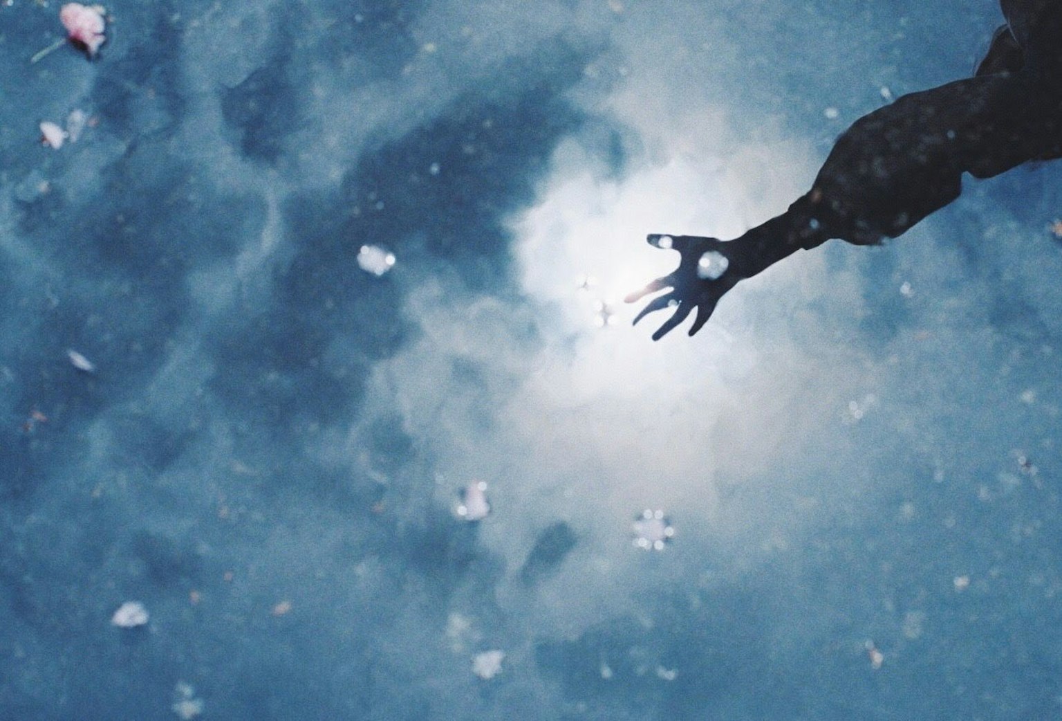 Une main tendue vers la lumière dans un ciel bleu