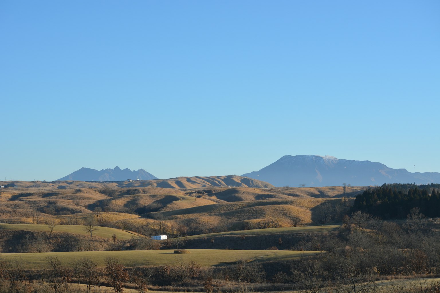 Rolling hills under a clear blue sky with distant mountains