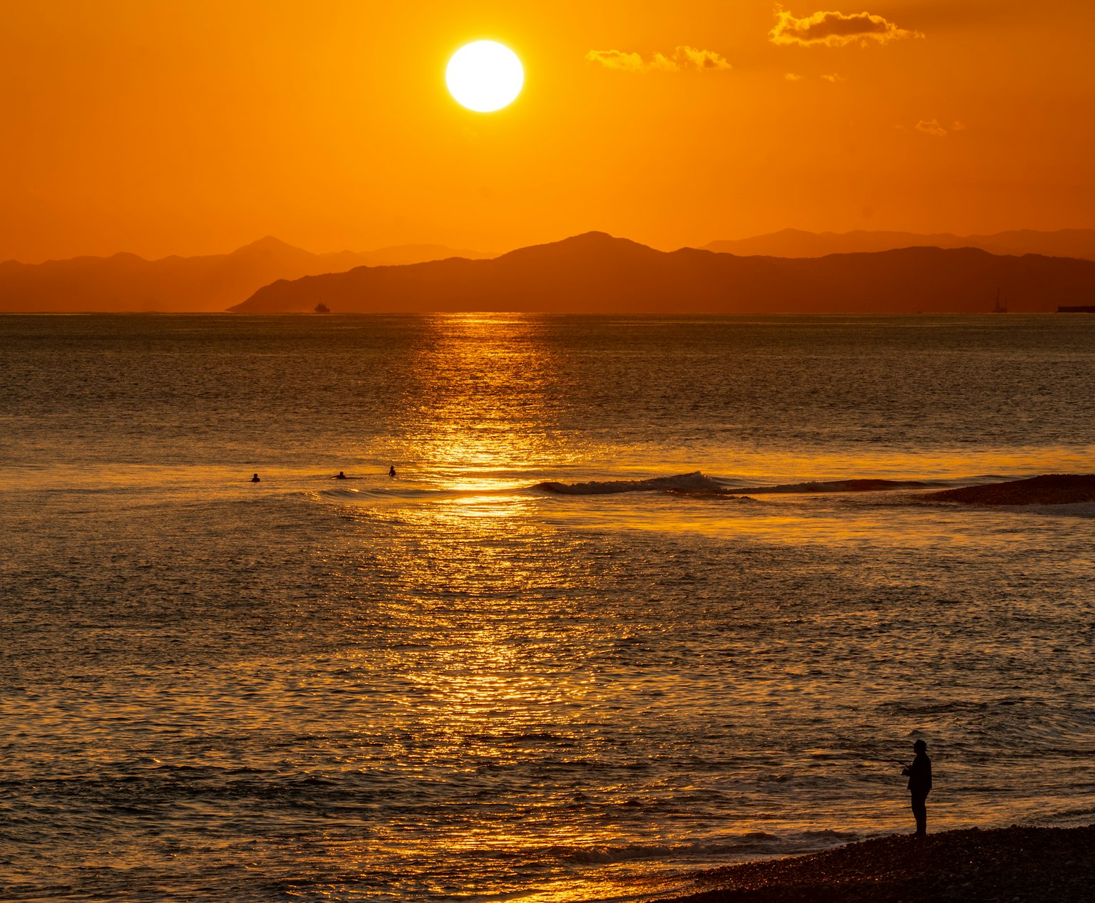 Un hermoso atardecer sobre el océano con una persona de pie en la orilla