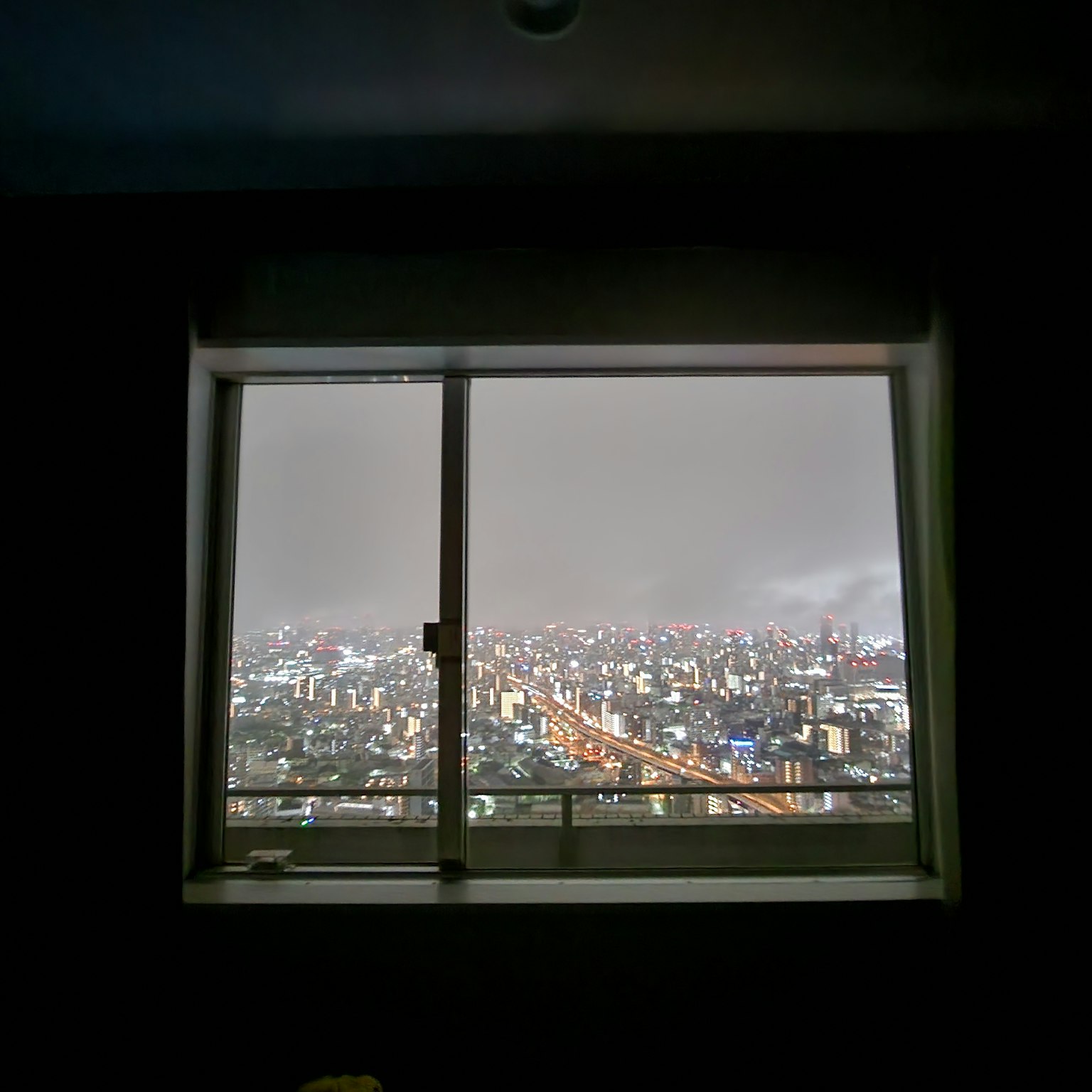 Vue de la ville depuis une fenêtre d'un gratte-ciel avec des lumières brillantes et un ciel brumeux