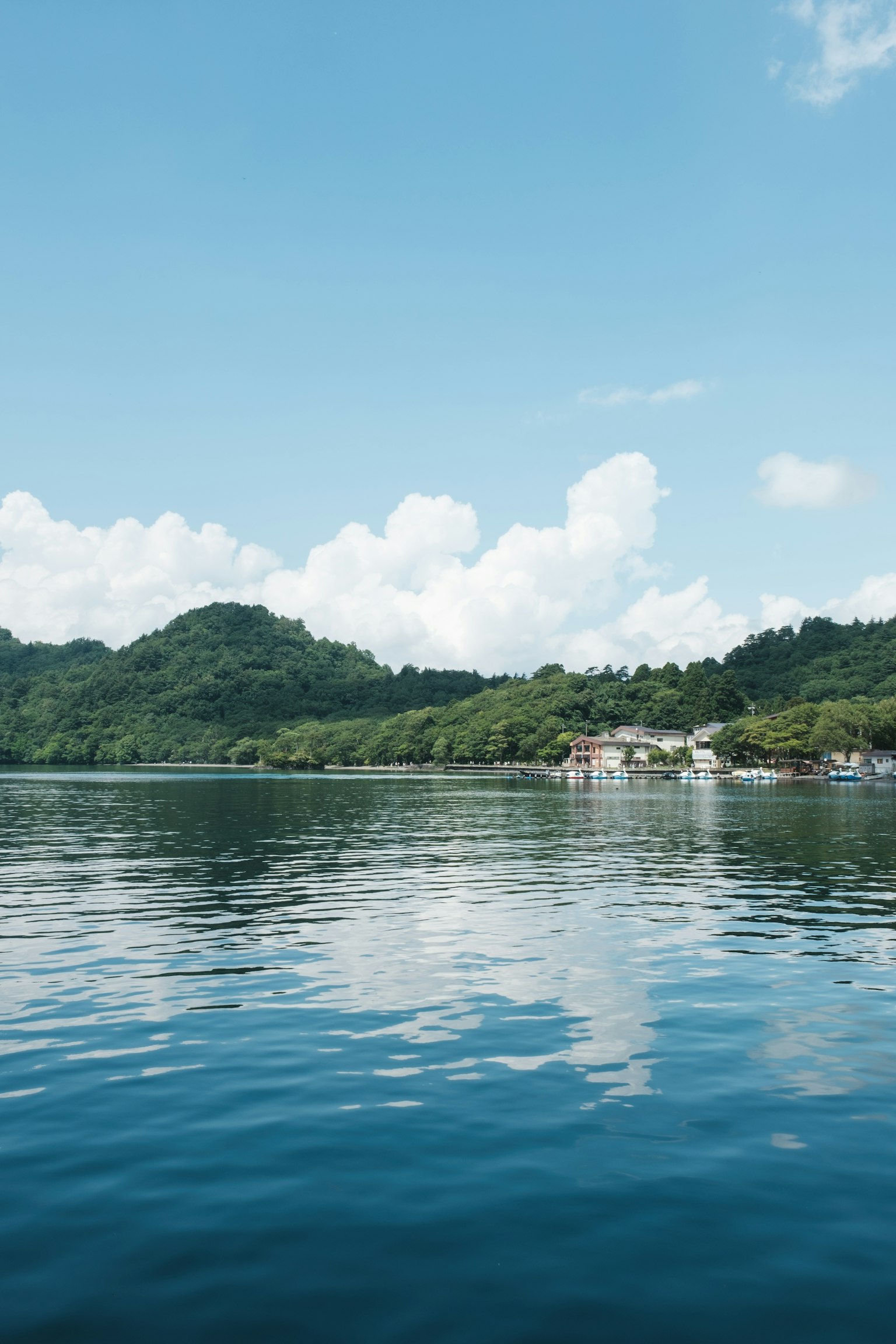 蓝色水面下的绿色山丘和白云的风景