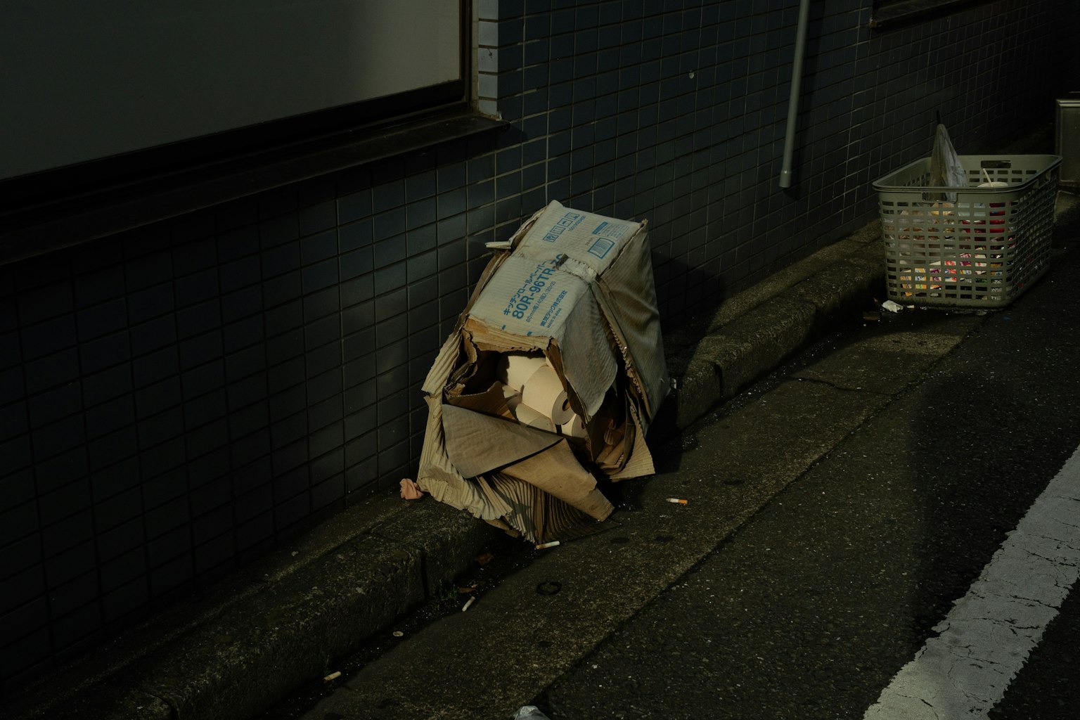 Montón de cajas de cartón en la calle junto a un cubo de basura