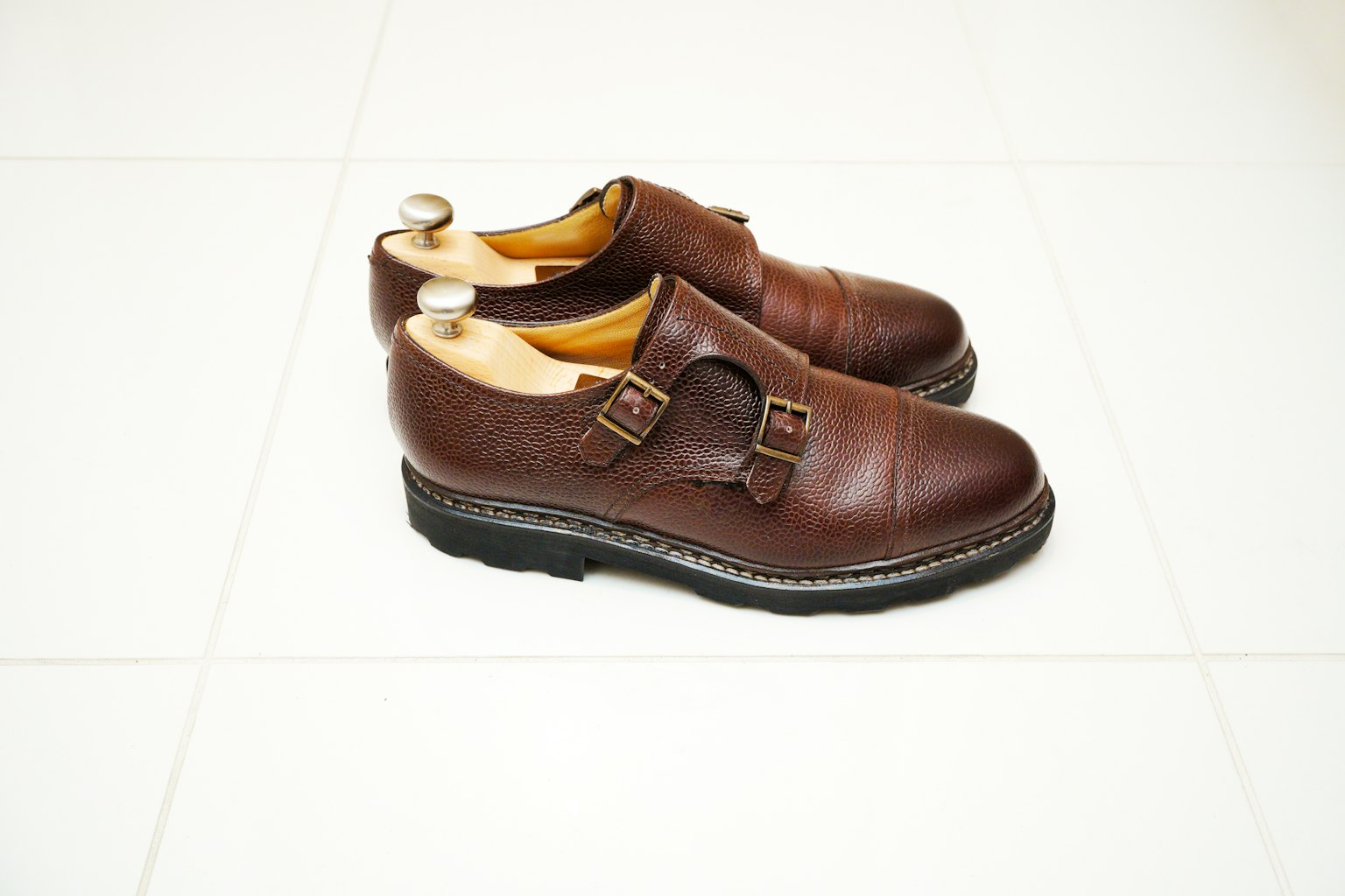 Brown leather shoes with buckles on a white floor