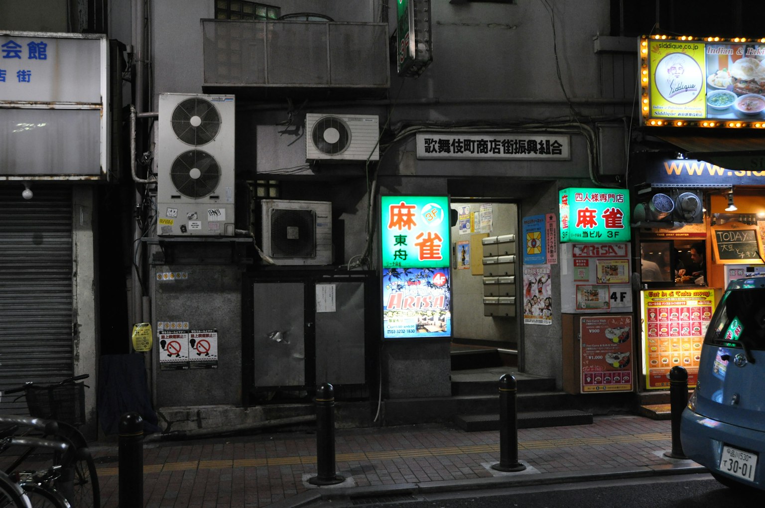 夜間小商店的外觀，明亮的霓虹燈和空調單元