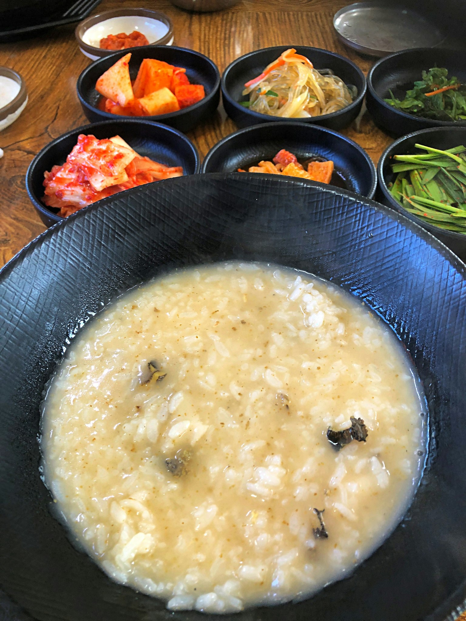 Porridge di riso in una ciotola nera con contorni di kimchi